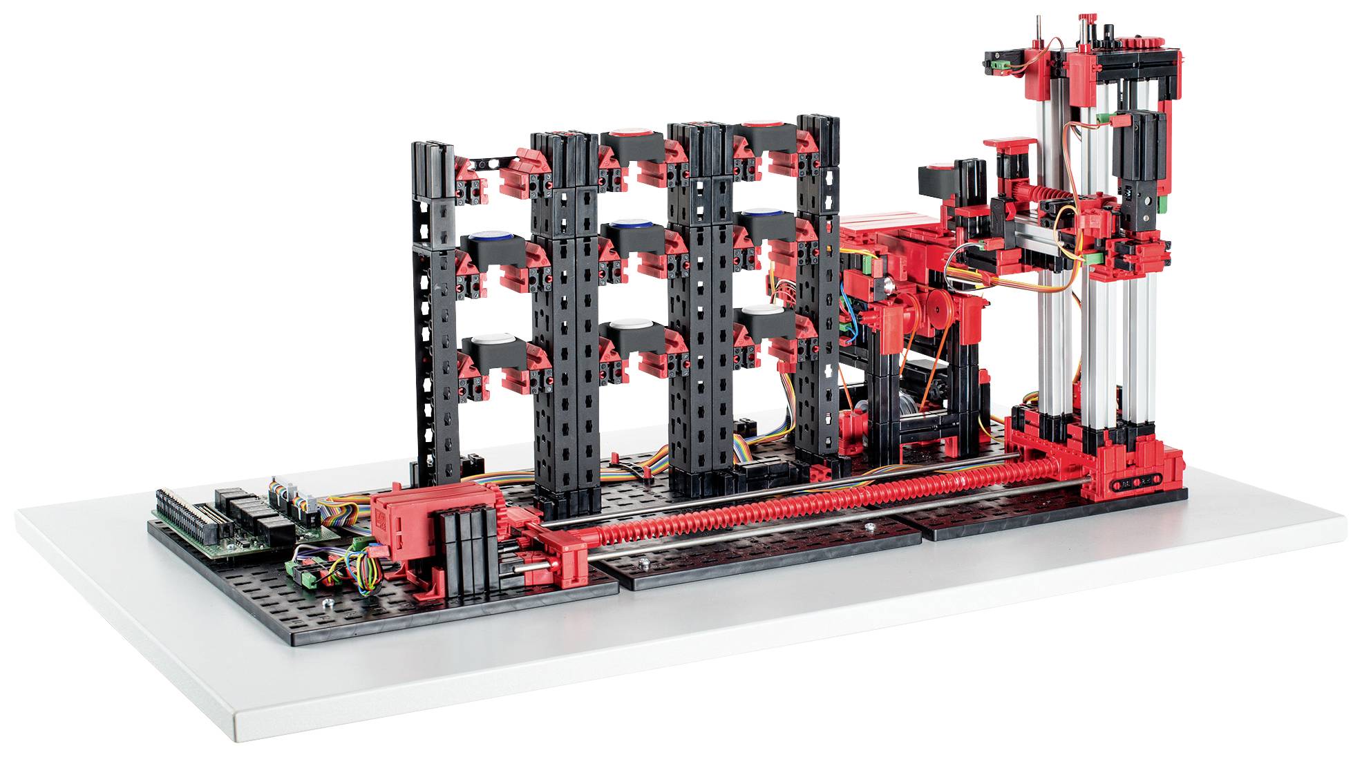 Komplexný mechanický model z čiernych a červených stavebných blokov, ktorý pripomína vertikálnu konštrukciu, umiestnený na bielom pozadí.