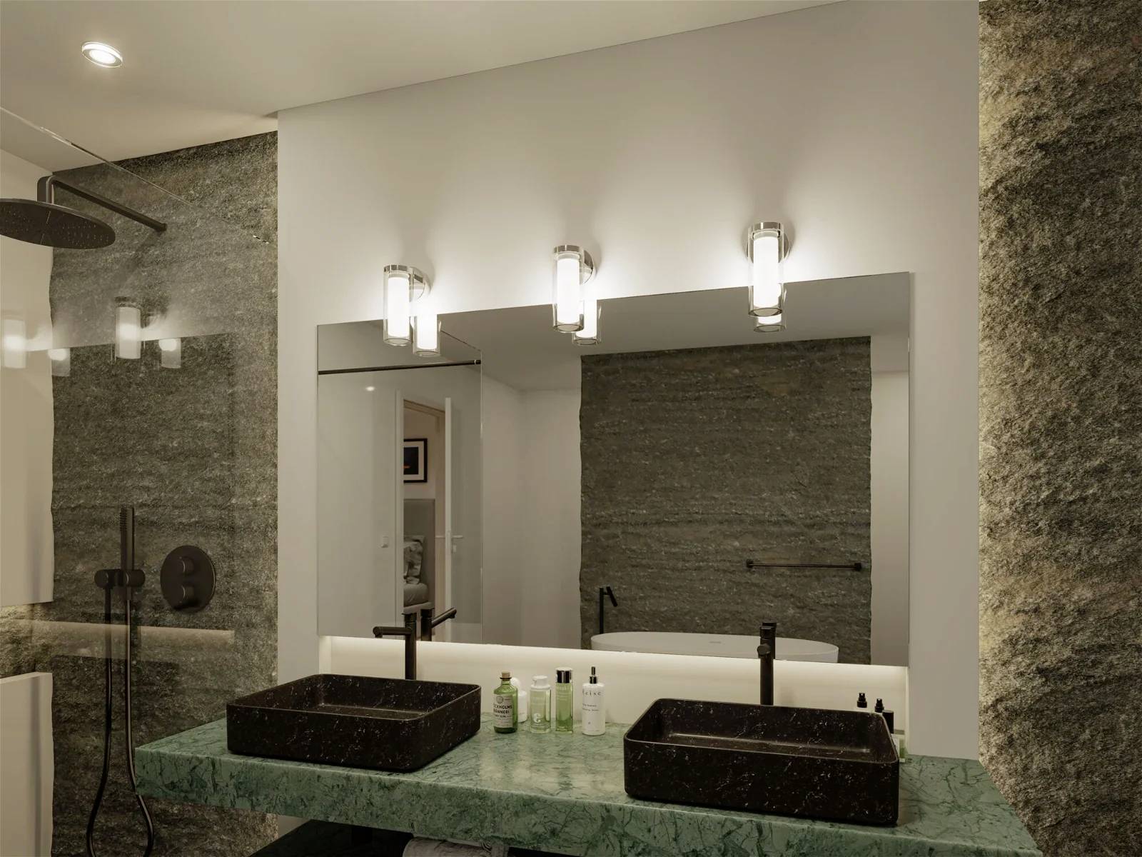 Moderná kúpeľňa s dvomi čiernymi umývadlami na zelenej mramorovej doske, zrkadlo a osvetlenie. Steny z tmavosivého kameňa.
