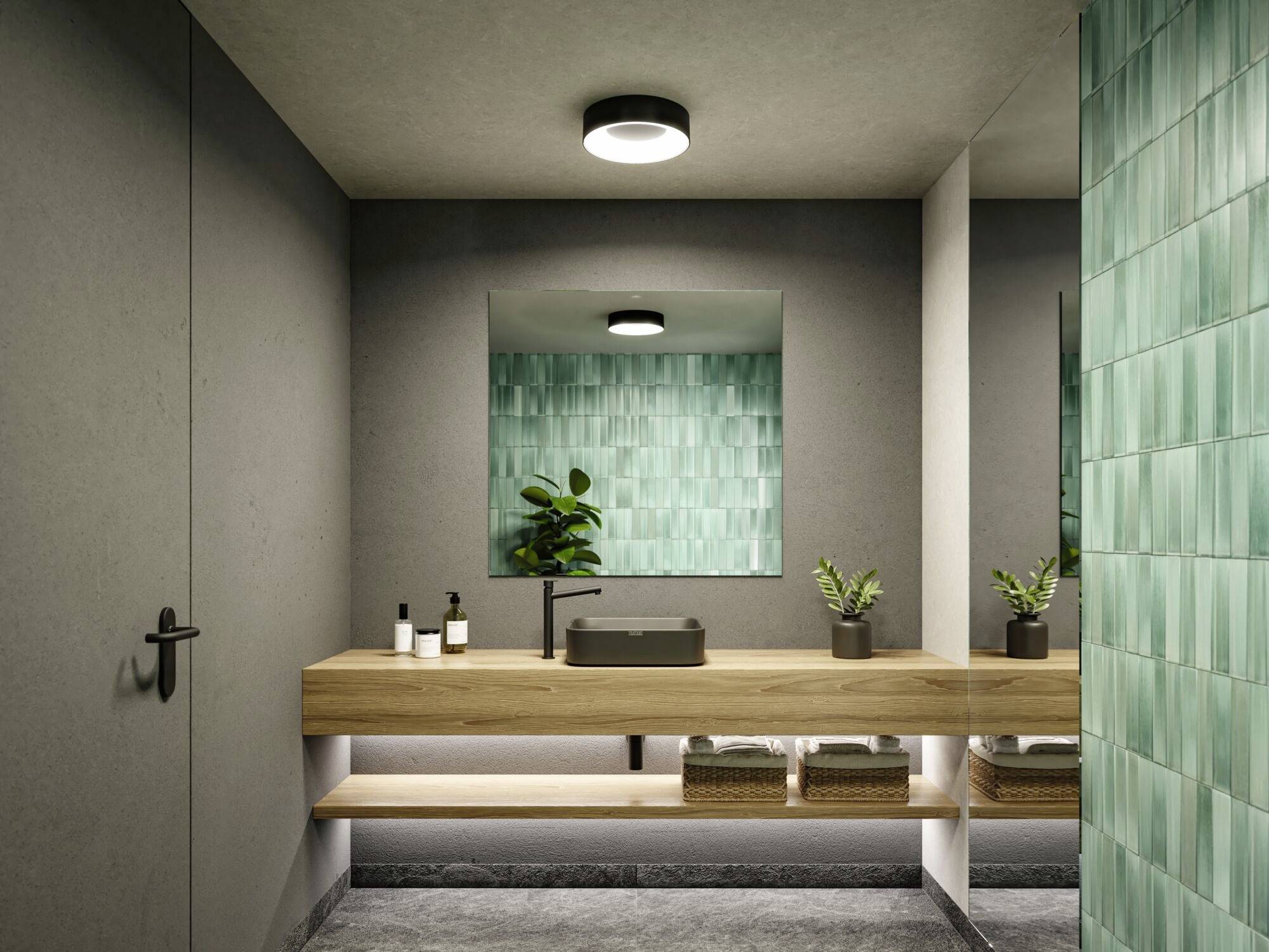 Moderný pohľad na kúpeľňu: stena obložená zelenými obkladačkami, drevená pracovná doska s čiernym umývadlom, dve rastliny, tlmené svetlo.