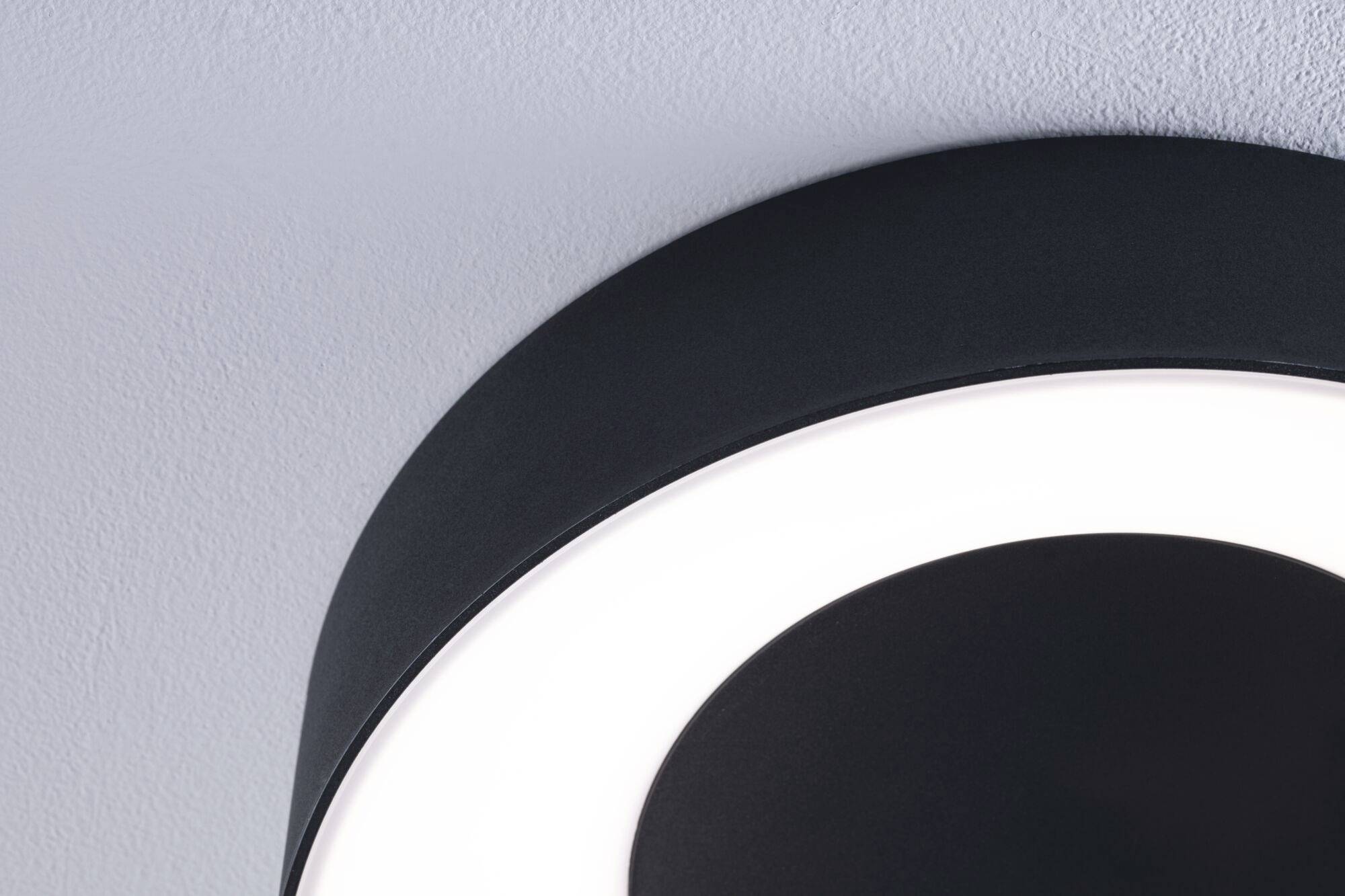 Okrúhle stropné svietidlo v čiernej farbe s jasným svietiacim prsteňom, namontované na sivom strope.