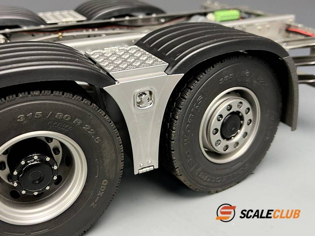 Detailný záber podvozku modelového nákladného auta s dvoma čiernymi pneumatikami a striebornými diskami. V pozadí sa nachádza logo 'ScaleClub'.