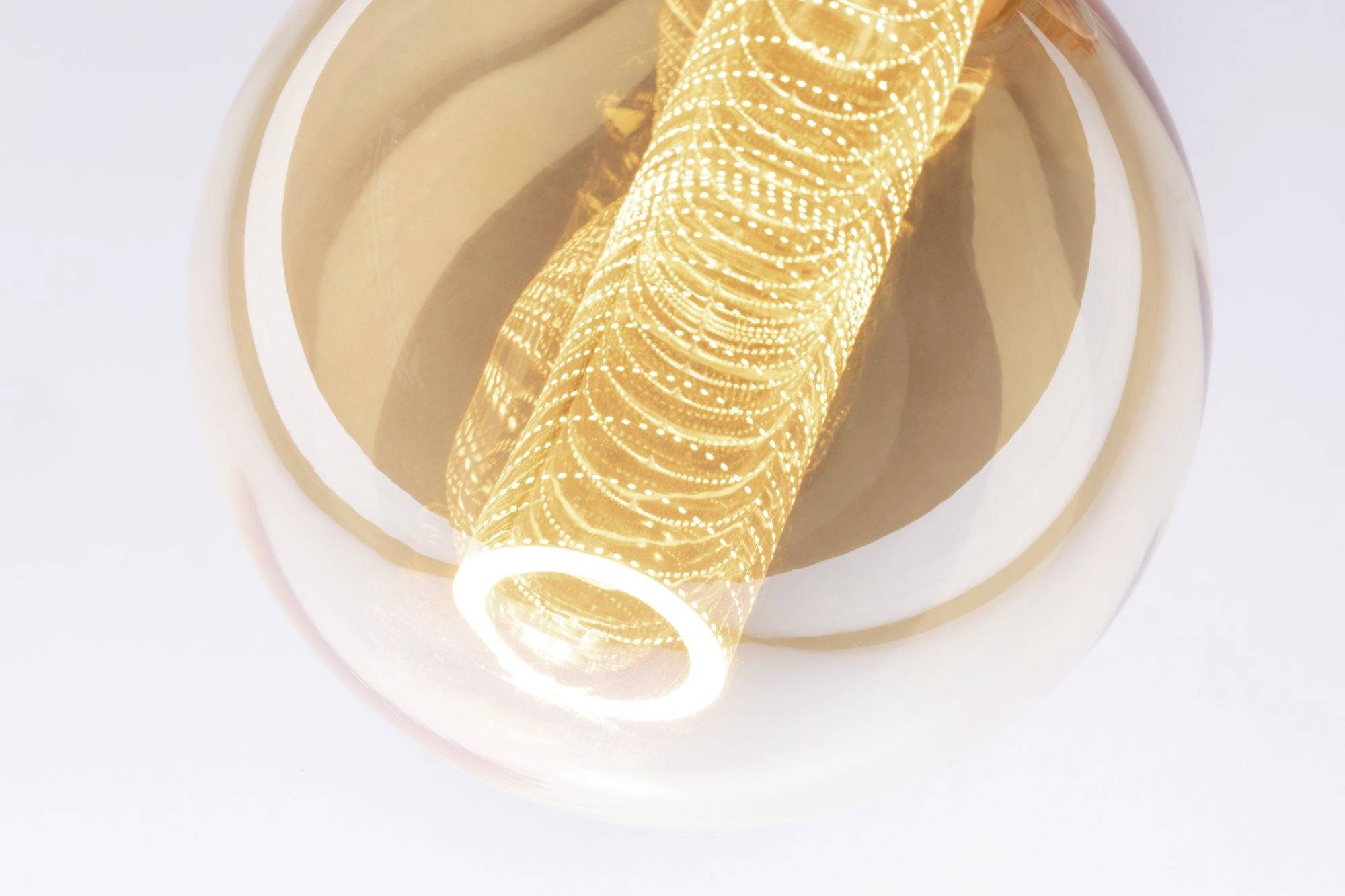 Detailný záber žeraviacej LED-filamentovej žiarovky v priehľadnej sklenenej baňke. Špirály sú jasne osvietené a zlatistej farby.