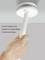 Ruka testuje okrúhly detektor dymu na strope pomocou dlhej tyče. Text: 'Veľké testovacie tlačidlo, veľmi praktické pre pravidelné kontroly funkčnosti'.