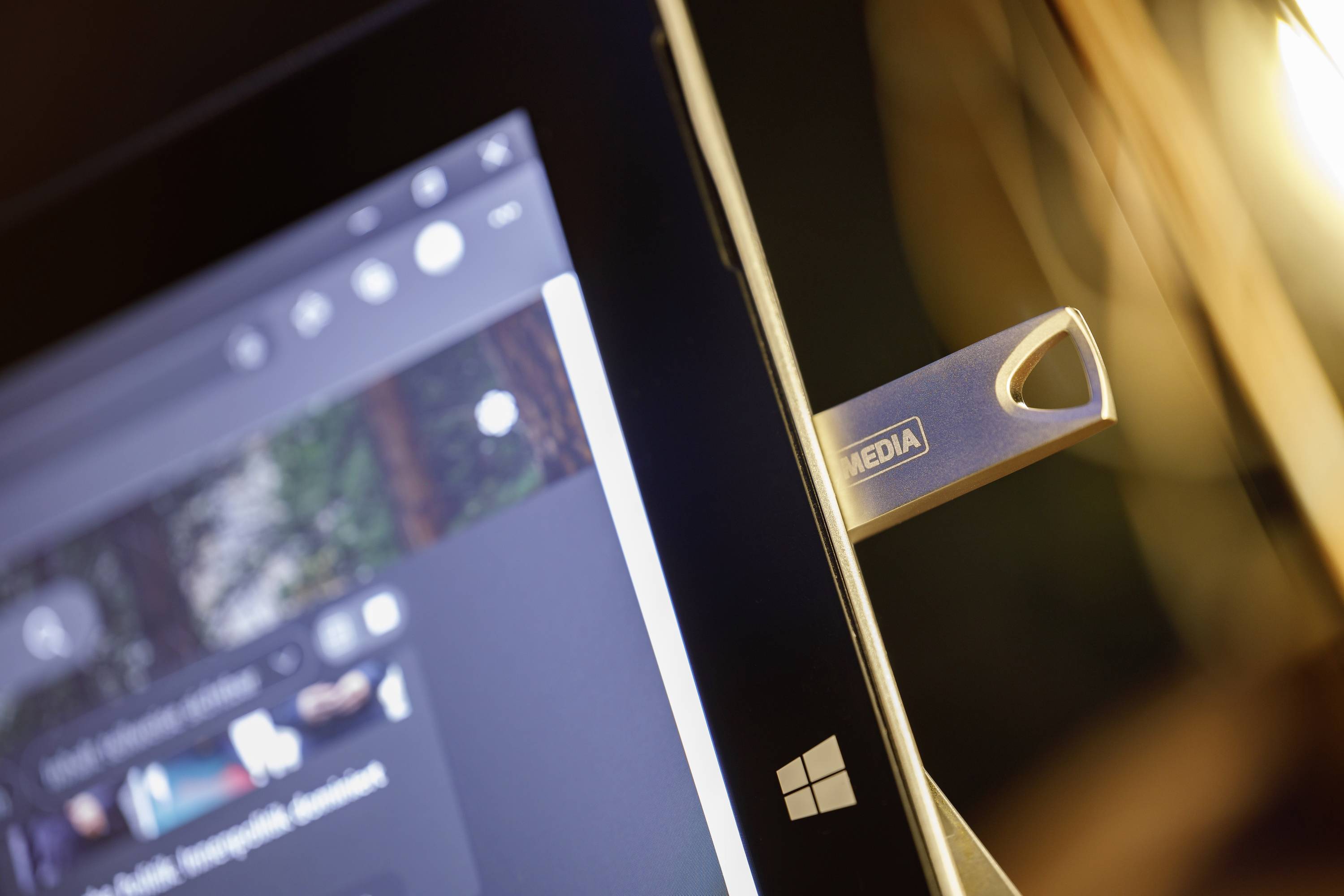 Tablet s logom Windows, USB kľúč označený ako 'MÉDIA' zasunutý. Obrazovka zobrazuje rozmazané obsahy. Zameranie na využitie technológie.