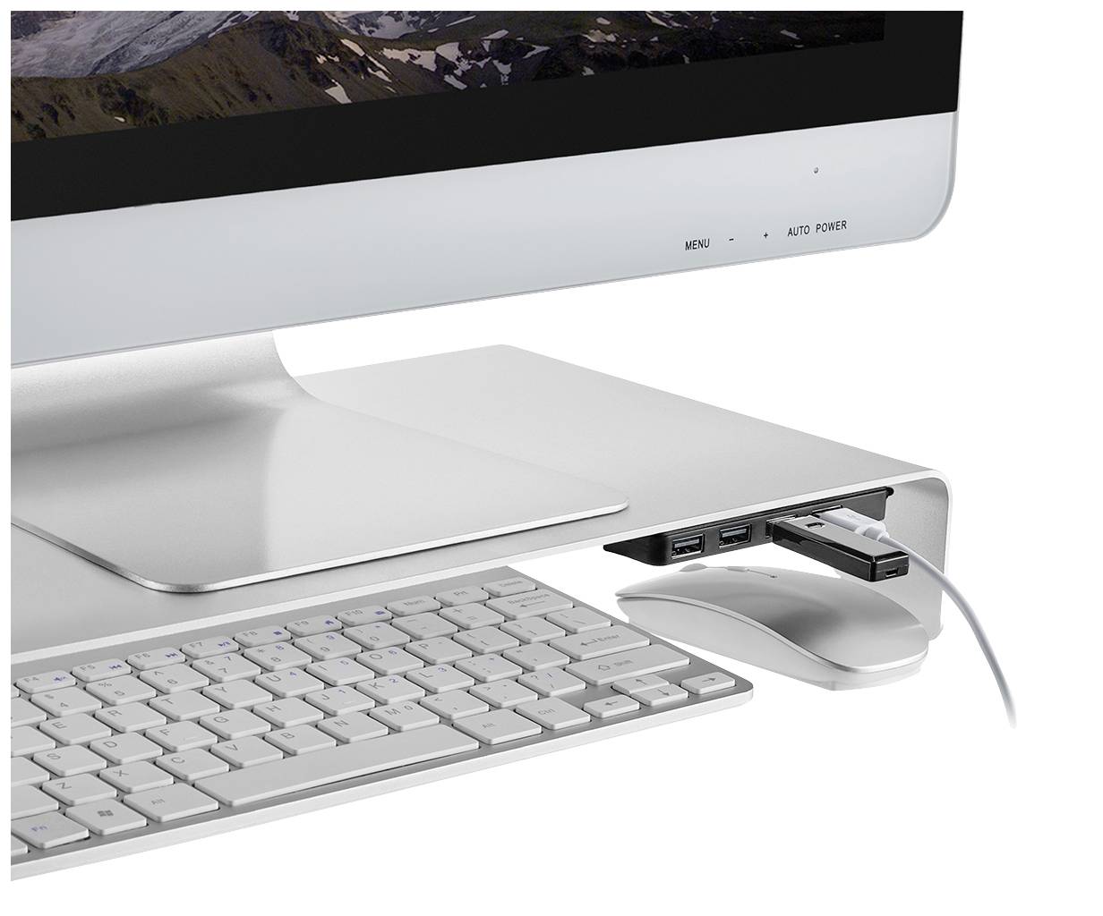 Počítačový monitor s vyvýšeným hliníkovým krytom, pod ktorým sa nachádza klávesnica a myš. Na kryte sú pripojené USB zariadenia.