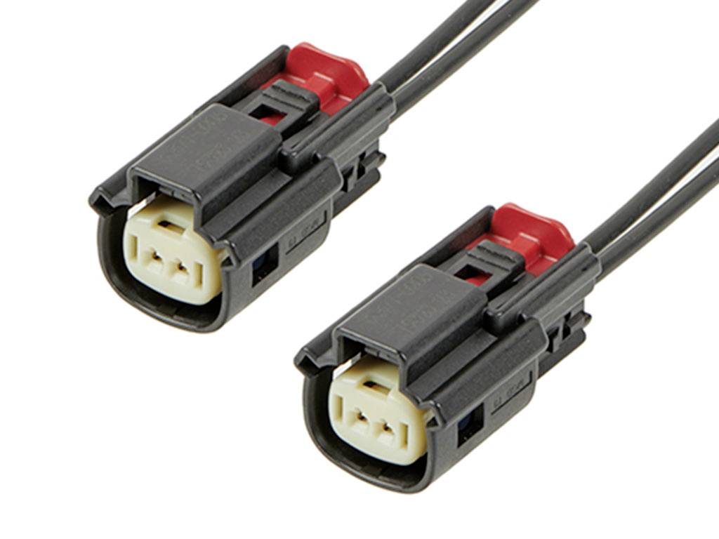 Dva čierne elektrické konektory s červenými svorkami, prepojené káblami; zobrazujú kontakty a sú pripravené na použitie v obvode.