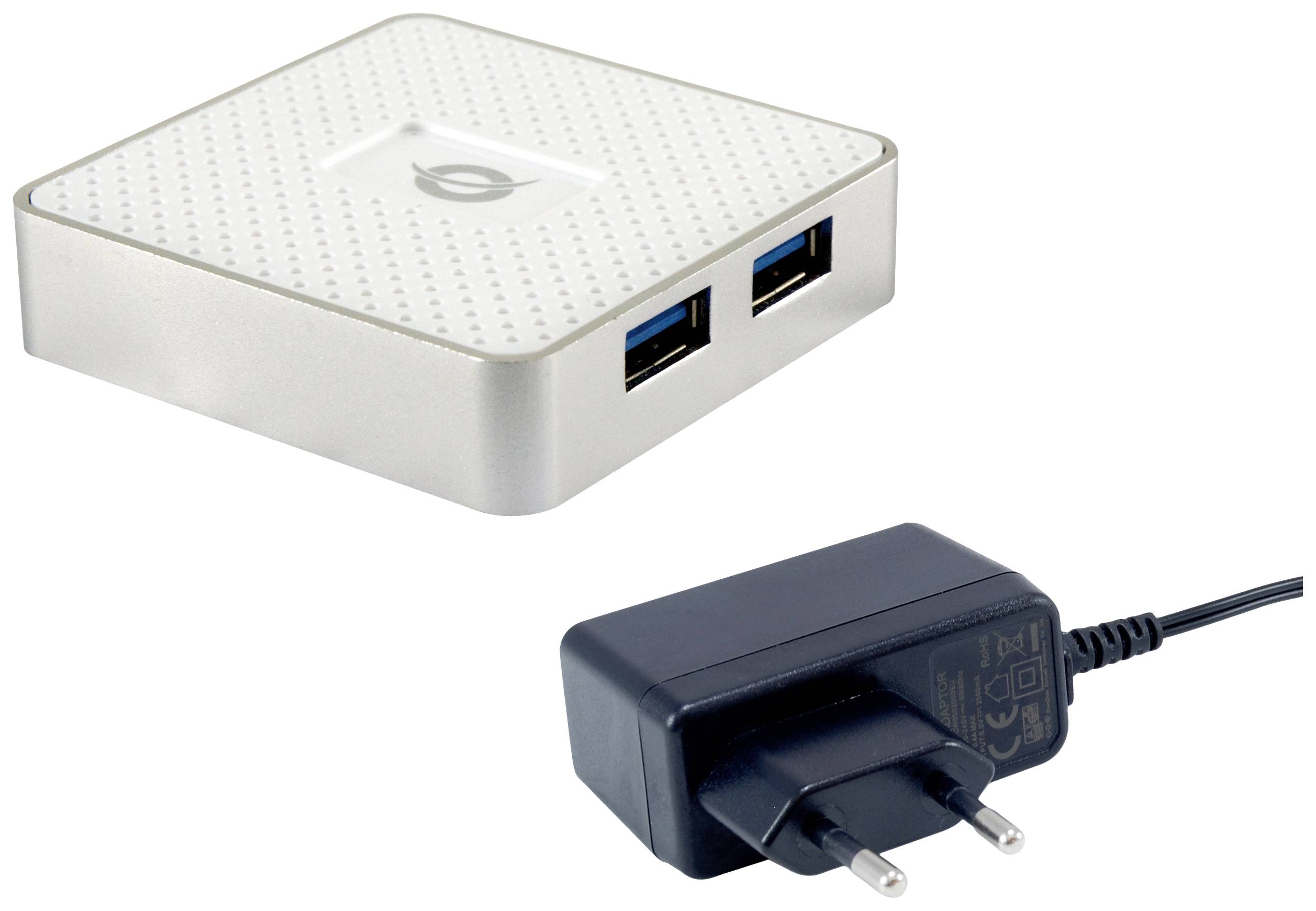 Malé biele USB zariadenie s dvoma portami leží vedľa čierneho sieťového adaptéra.