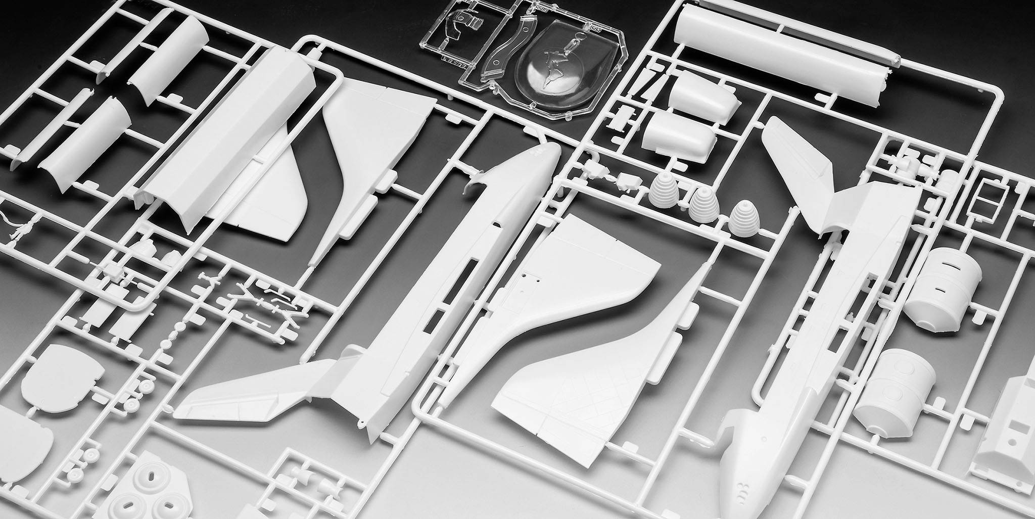 Stavebnica modelu lietadla z bieleho plastu. Rôzne časti lietadla sú usporiadané v mriežkovom ráme.