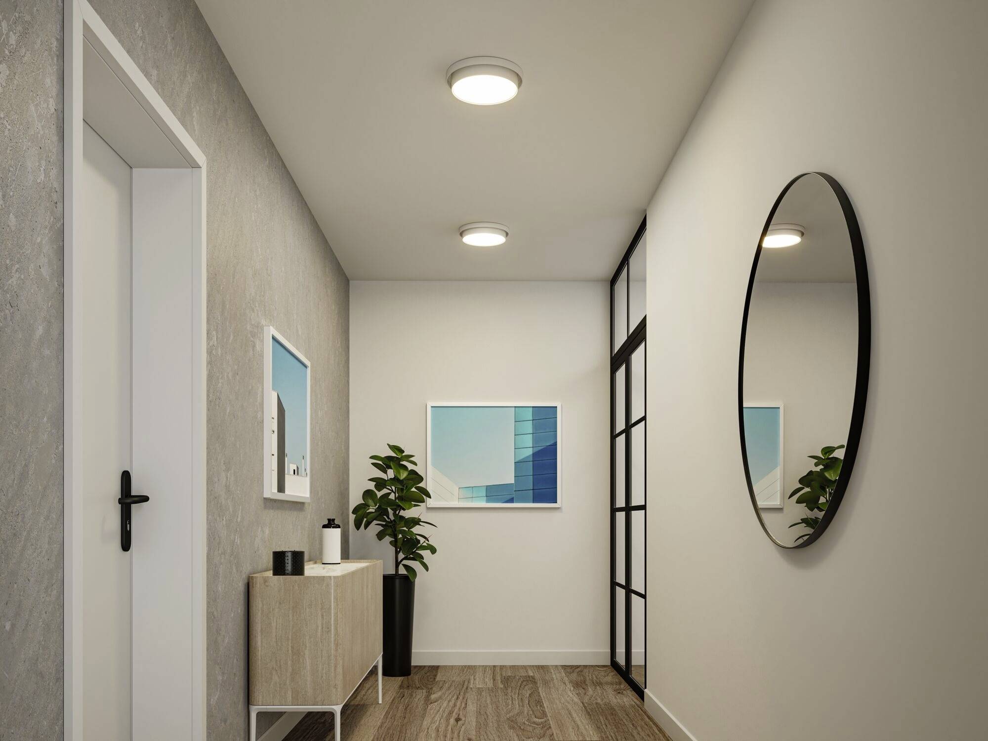 Moderná chodba s drevenou podlahou, okrúhlym zrkadlom na stene, dvoma stropnými svietidlami, obrazmi a rastlinou na skrini.