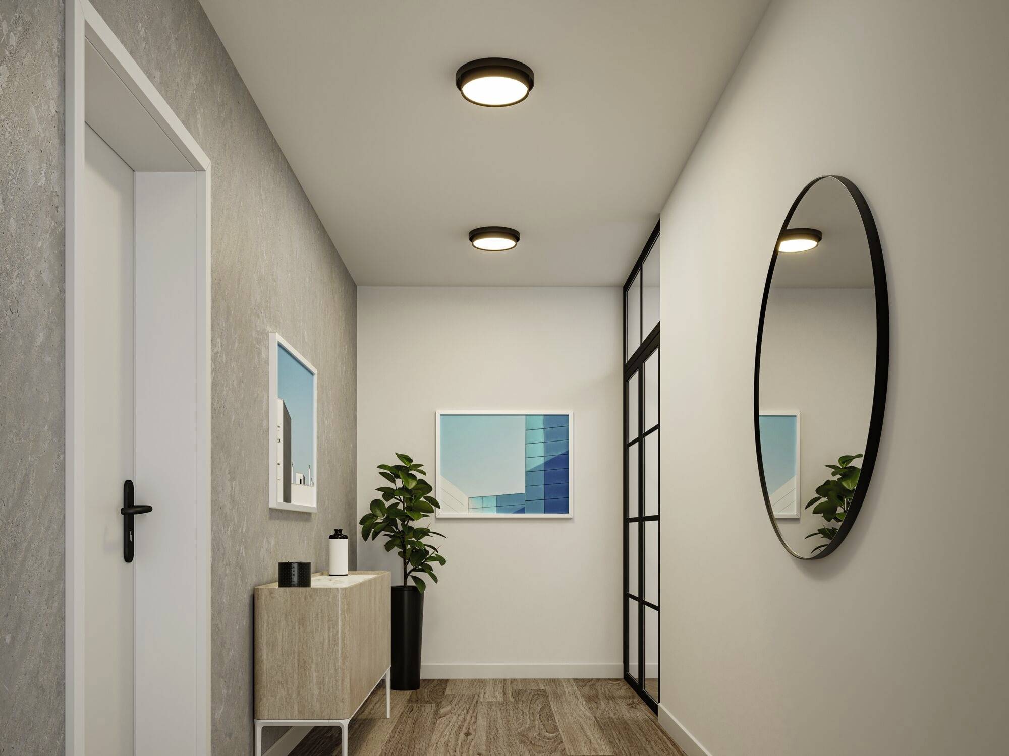 Moderne zariadenej chodby s drevenou podlahou, okrúhlym stenným zrkadlom, príborníkom a rastlinami. Na stene visia dva obrazy.