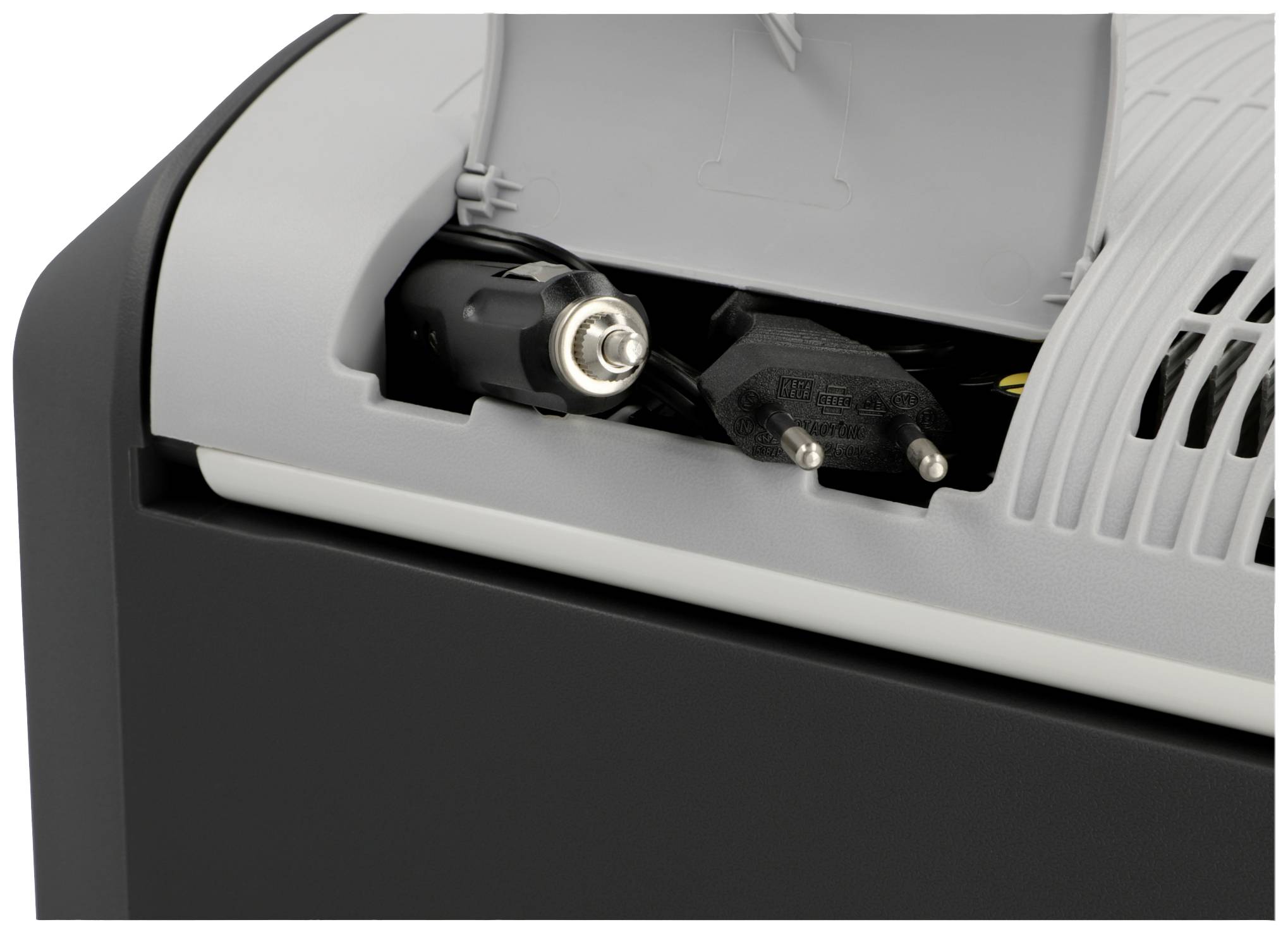 Elektronické zariadenie s otvoriteľným priestorom, v ktorom sú uložené rôzne káble a sieťová zástrčka.