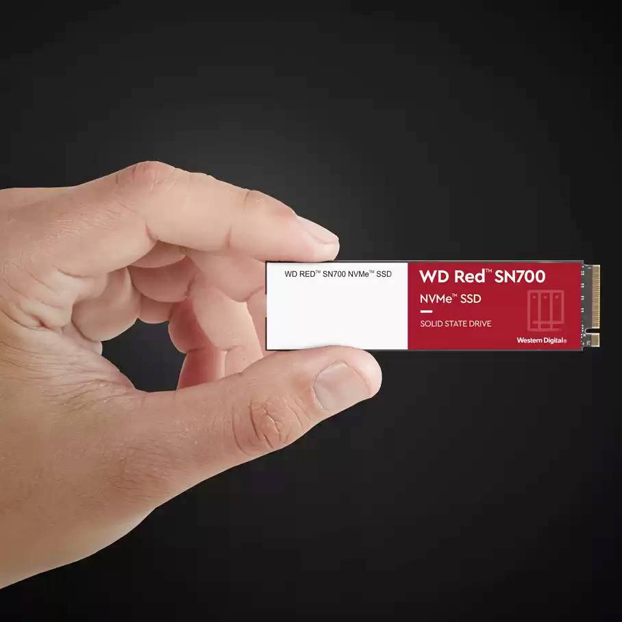 Jedna ruka drží WD RED SN700 NVMe SSD, úložné médium s červeným štítkom, ktorý symbolizuje vysokú rýchlosť a výkon.
