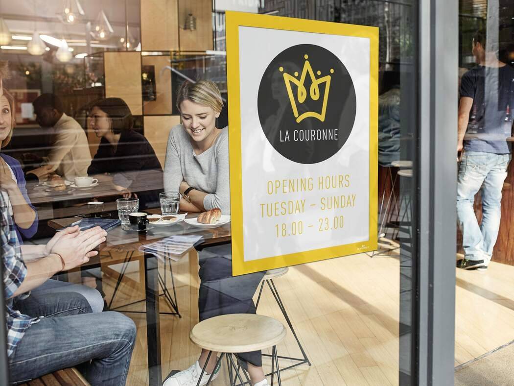 Kaviareň so scénou ľudí pri stoloch, vonku je cedula so zlatou korunou a nápisom 'La Couronne'. Otváracie hodiny: Utorok-Nedeľa, 18:00-23:00.