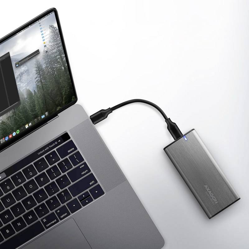 Laptop s pripojeným externým strieborným pevným diskom cez USB kábel, pripravený na prevádzku, signalizovaný modrým svetlom.