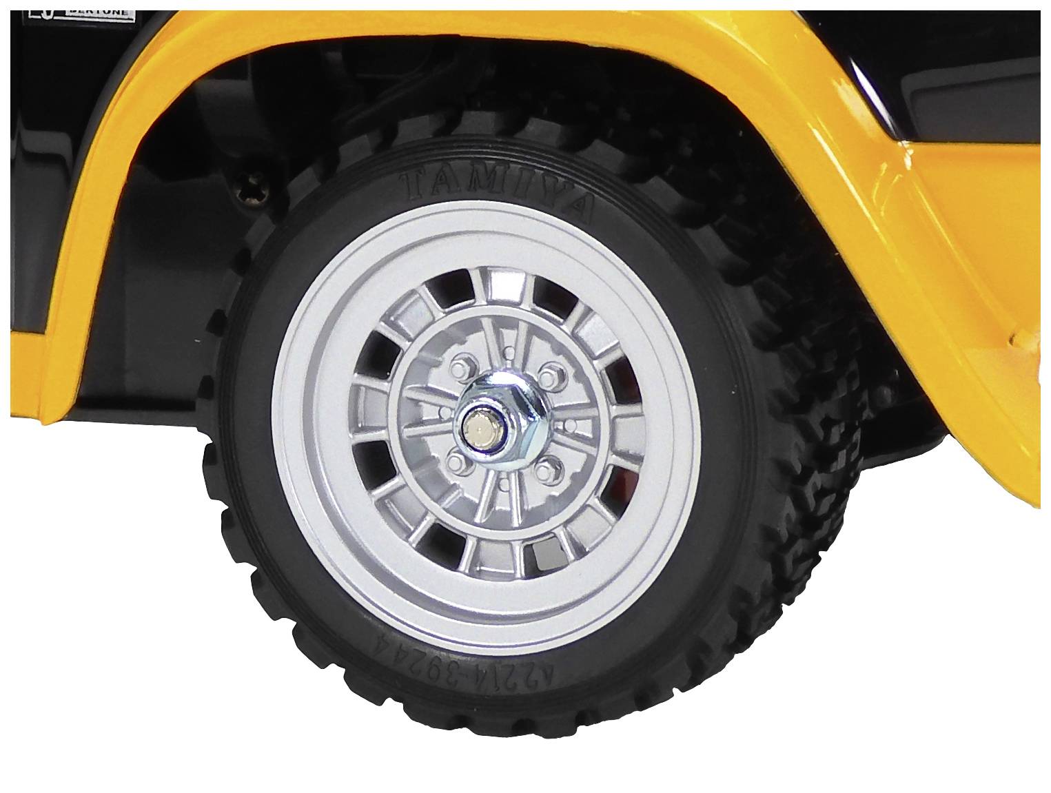 Koleso hračkárskeho autíčka s čiernou pneumatikou a strieborným ráfikom. Vozidlo je čiastočne natreté oranžovou farbou.