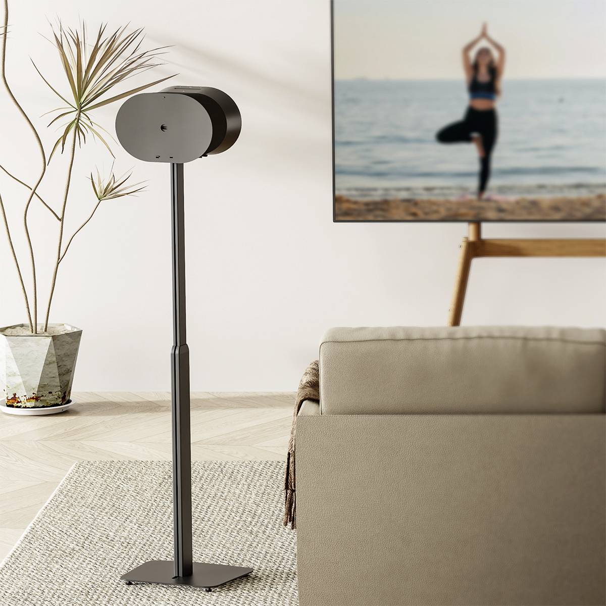 Obývacia izba s moderným stojanom uprostred. Na pozadí televízor zobrazuje osobu cvičiacu jogu na pláži.