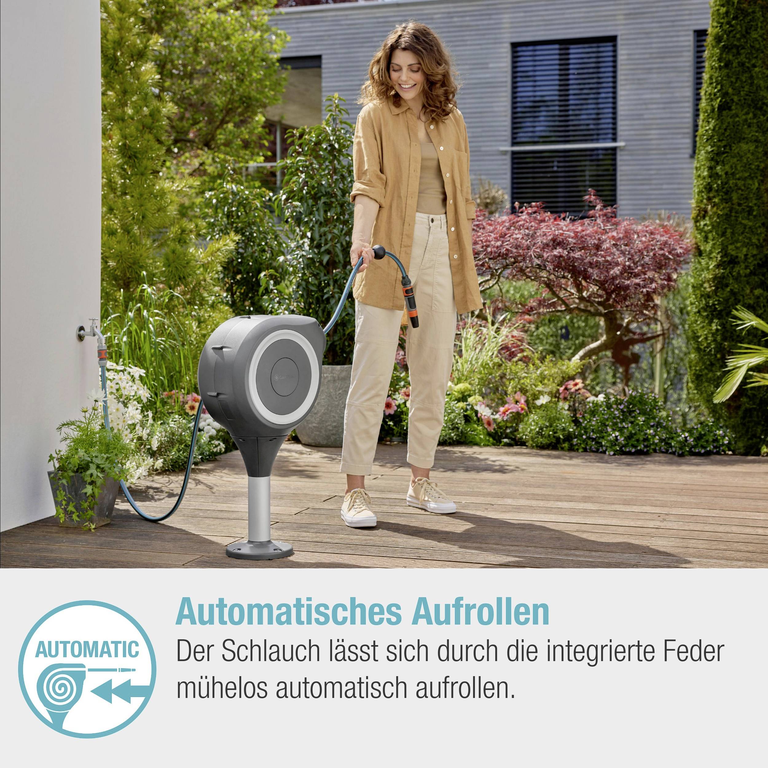 Žena ťahá záhradnú hadicu z automatického navíjacieho zariadenia v záhrade. V pravom dolnom rohu je uvedené: 'Hadica sa vďaka integrovanej pružine ľahko a automaticky navinie'.