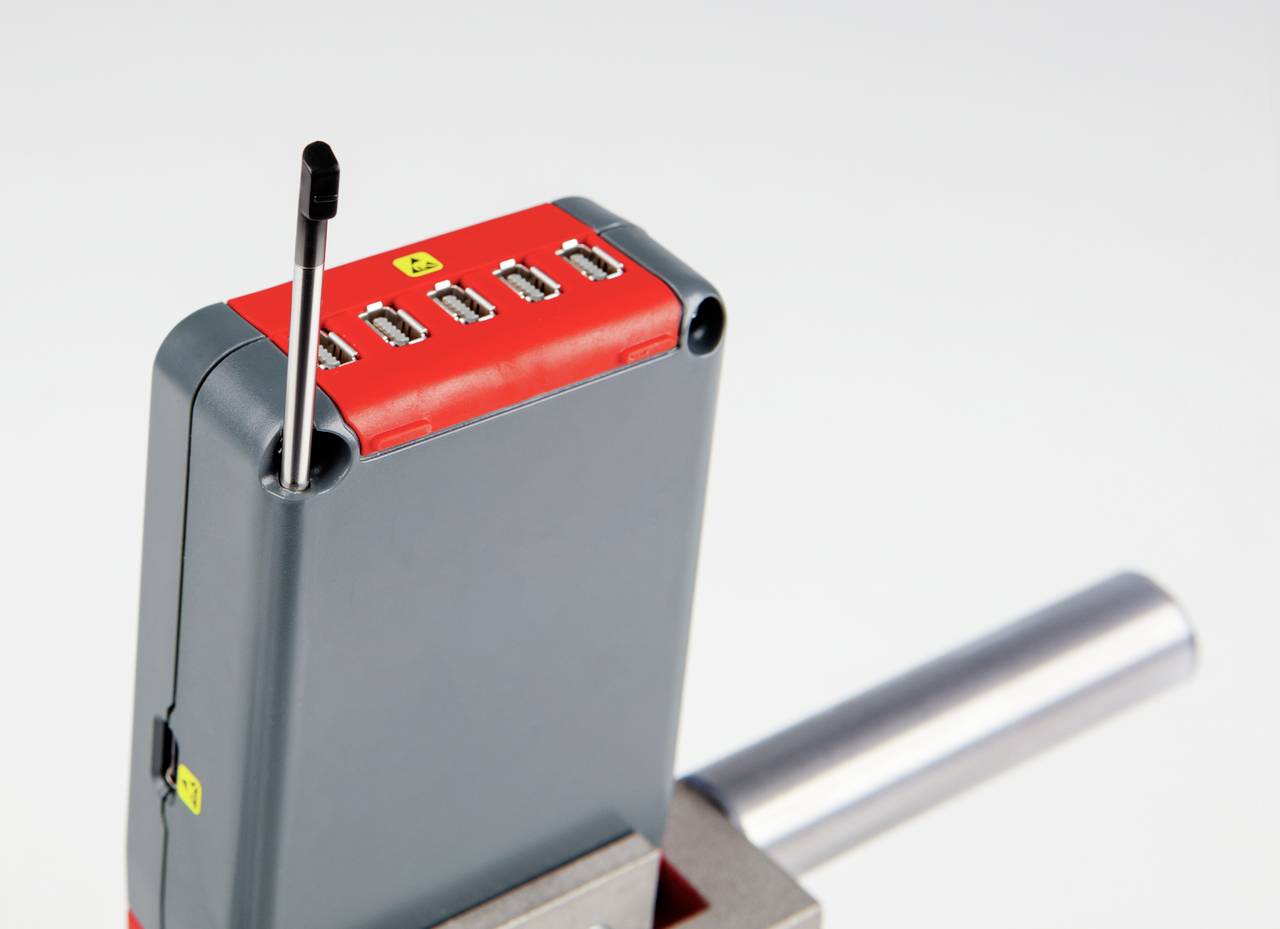 Sivé a červené elektronické zariadenie so štyrmi USB portami a vysunutou anténou, namontované na stole.