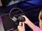 Osoba drží headset s mikrofónom pred počítačovou obrazovkou a podsvietanou klávesnicou. Vyzerá to ako herná scéna.