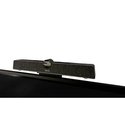 Soundbar sedí na monitore, jej predná strana je potiahnutá látkou a v strede je viditeľné lesklé, okrúhle logo.