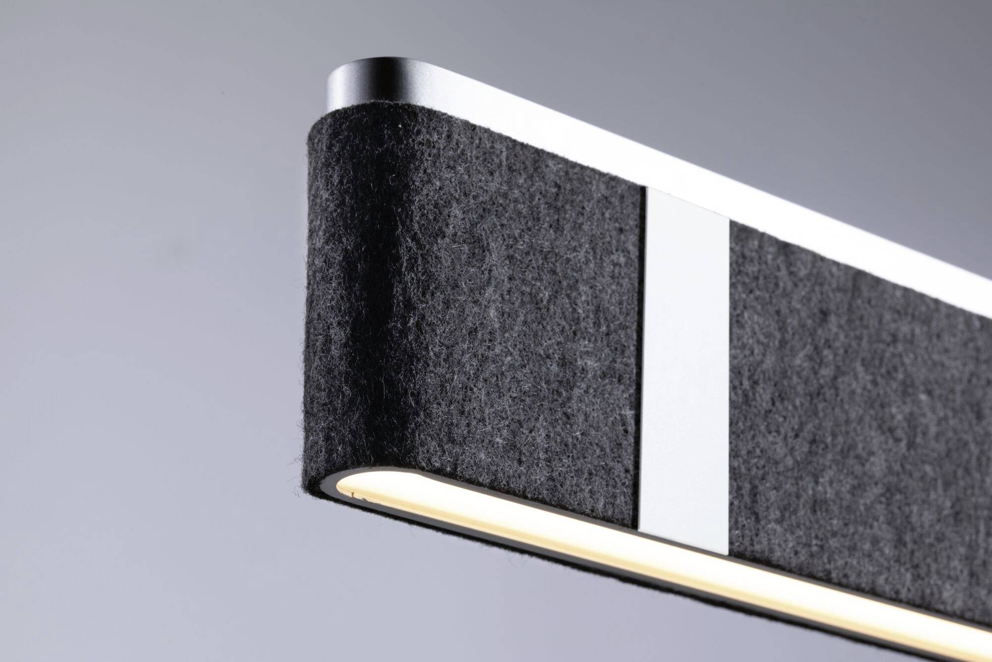 Moderná závesná lampa s plsteným poťahom a kovovými akcentmi, ktorá poskytuje jemné svetlo.