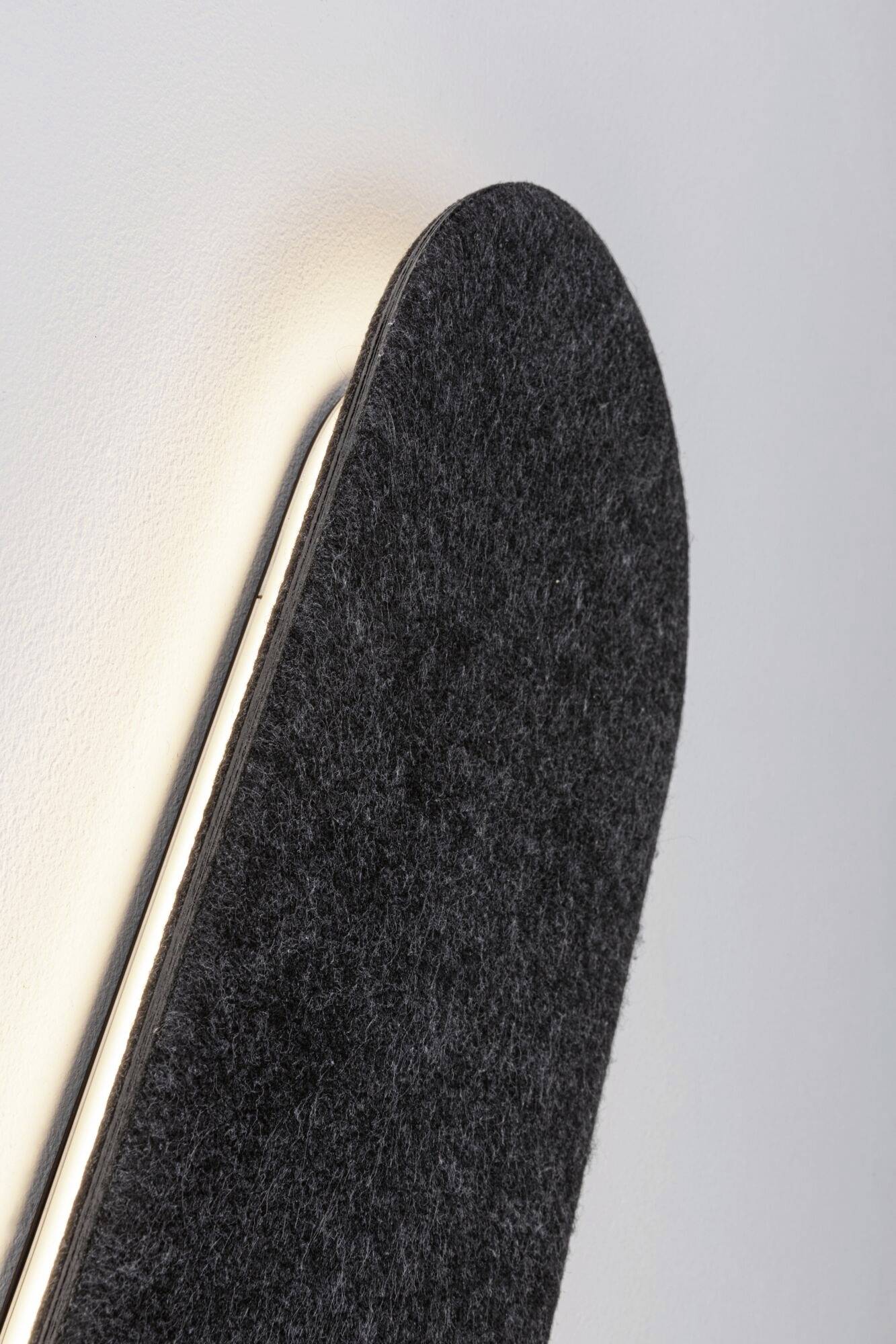 Nástenná zakrivená lampa s sivým plsteným poťahom a integrovaným LED osvetlením, ktorá vyžaruje jemné svetlo.