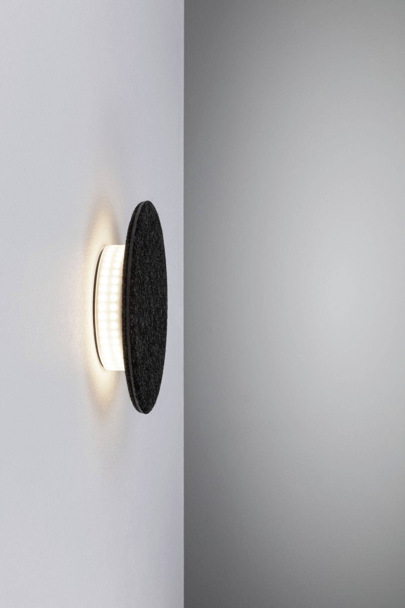 Moderná nástenná lampa s okrúhlym dizajnom vyžaruje jemné svetlo.