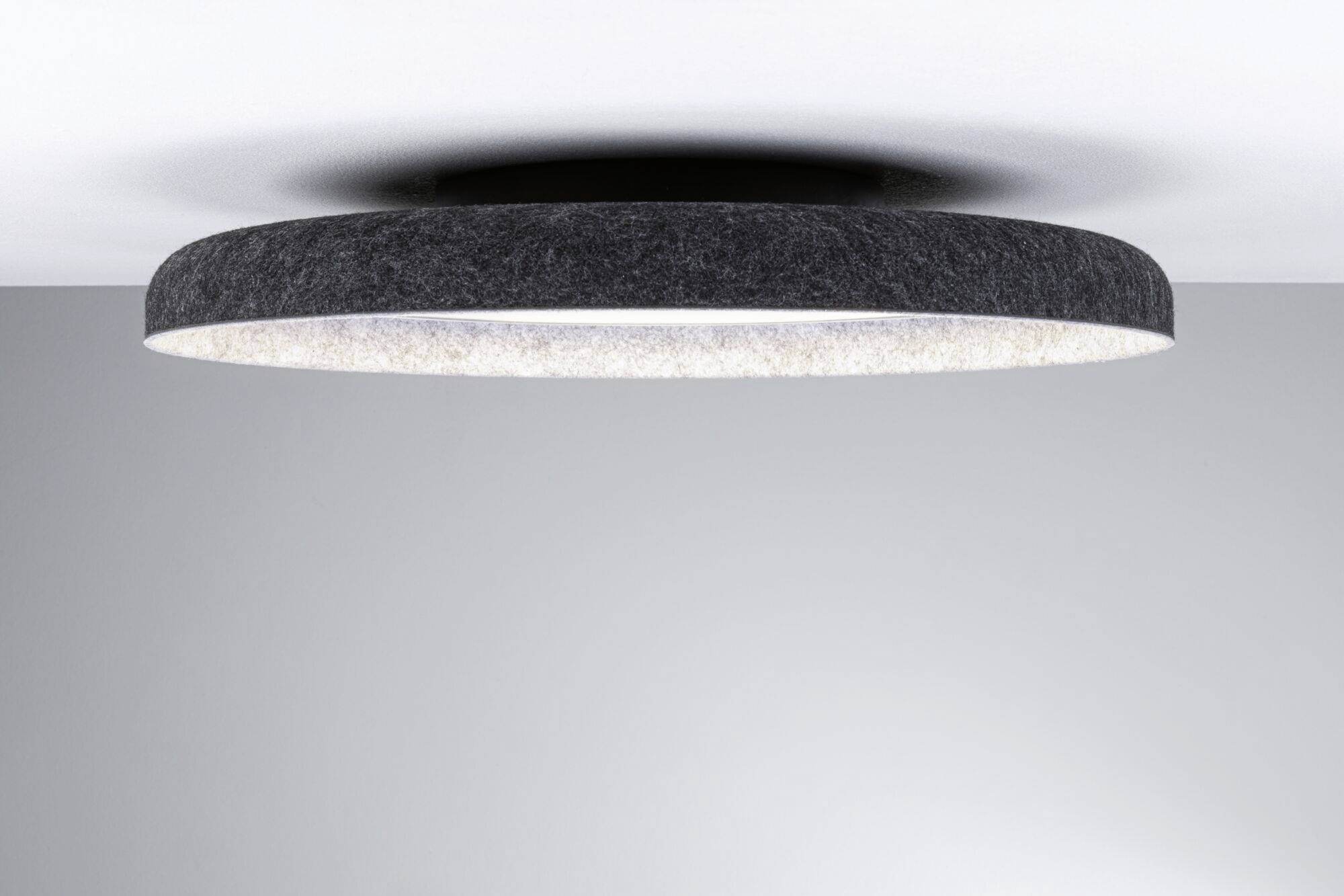 Okrúhle stropné svietidlo s tmavým okrajom a svetlým vnútorným priestorom, namontované na bielom strope. Moderný a minimalistický dizajn.