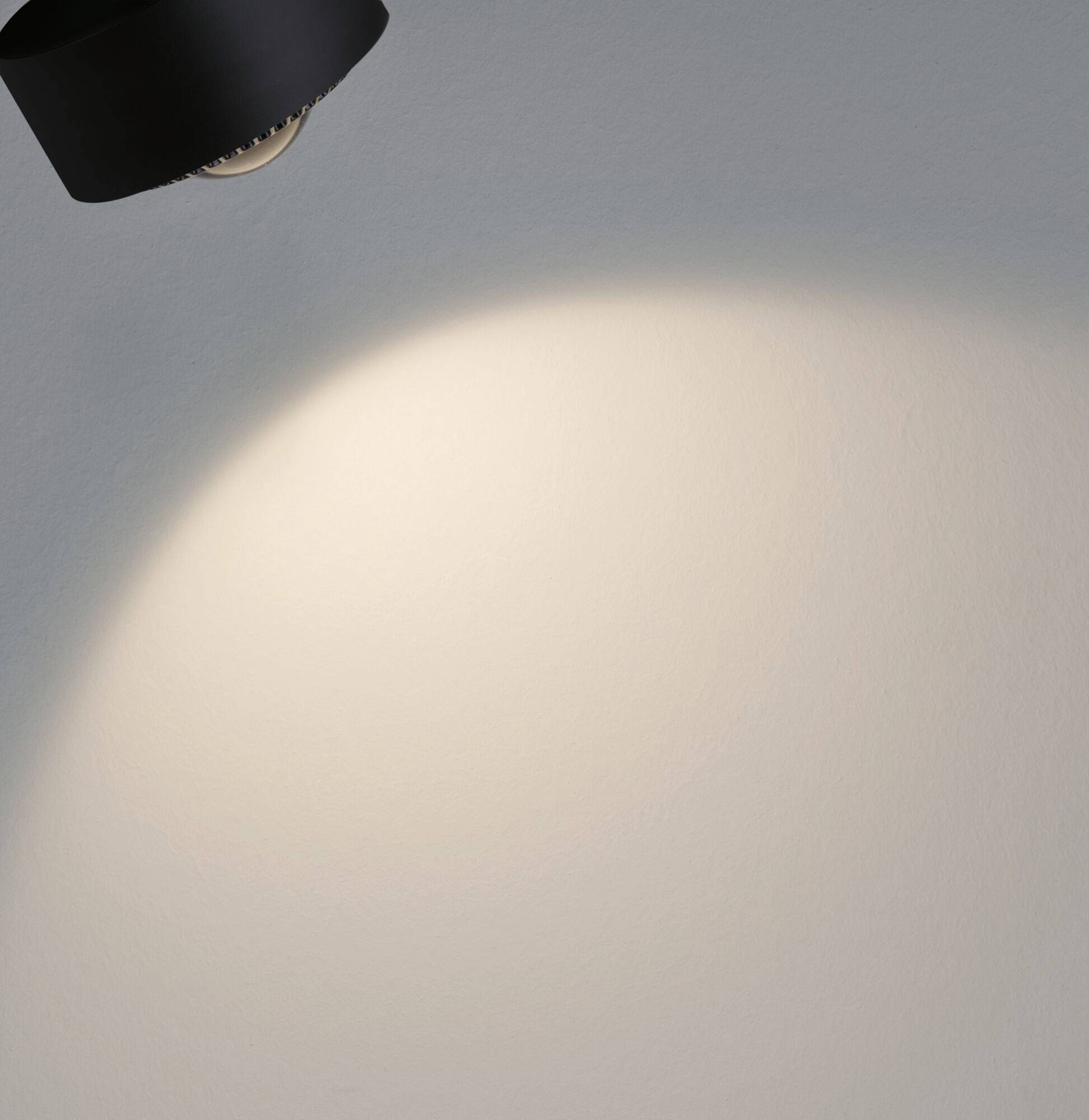 Lampa osvetľuje stenu, pričom svetelný kužeľ je smerovaný nadol.