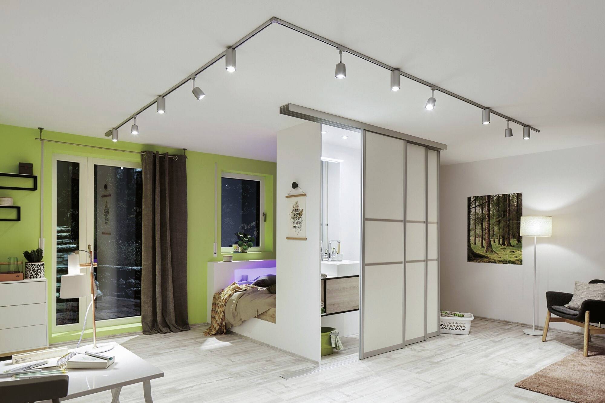 Obývačka so svetlou drevenou podlahou, zelenými stenami a moderným osvetlením. Spacia časť oddelená posuvnými dverami.