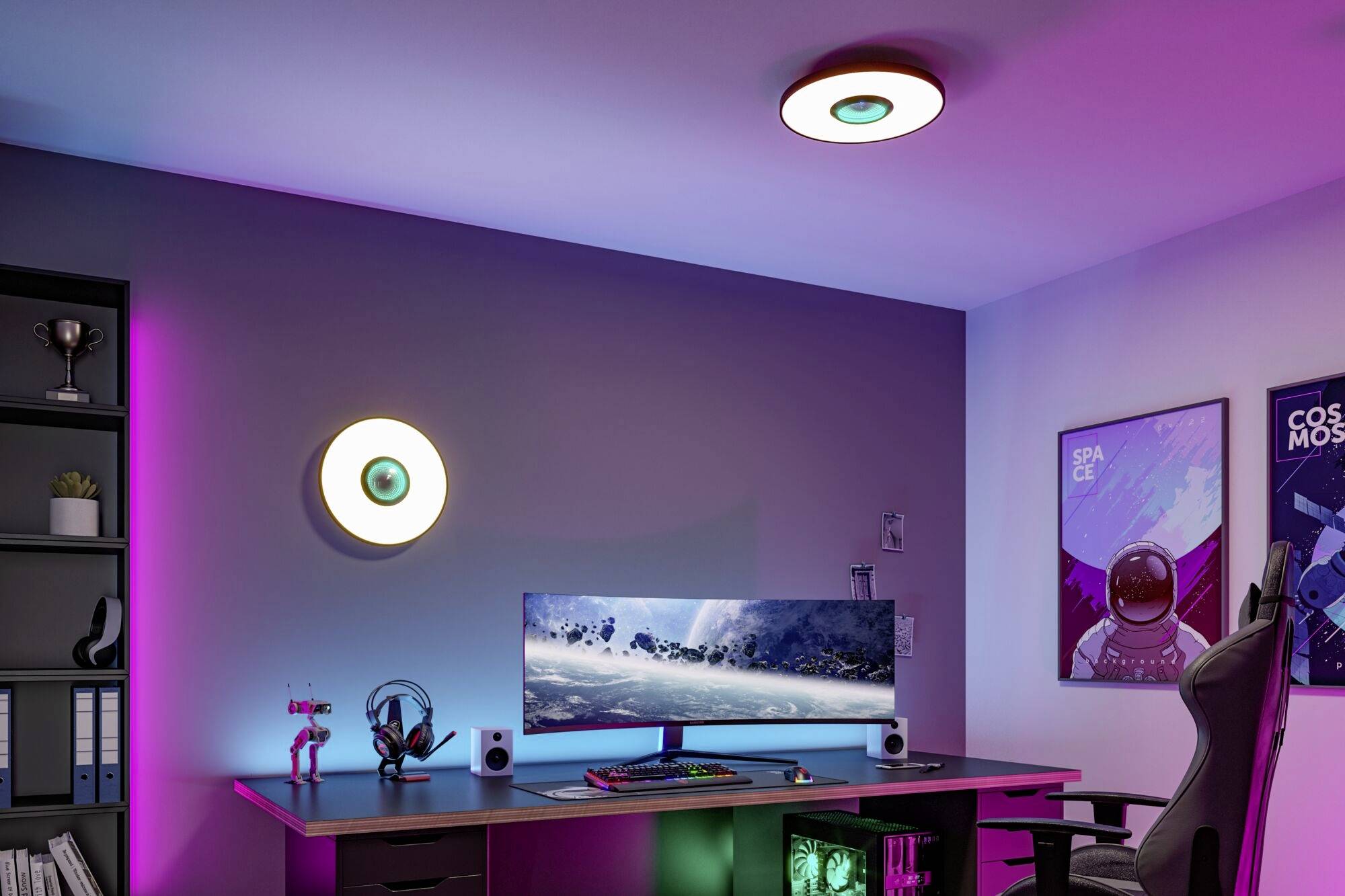 Moderný písací stôl s veľkým monitorom zobrazuje zimnú krajinu. Osvetlenie je viacfarebné a na stene sú plagáty.