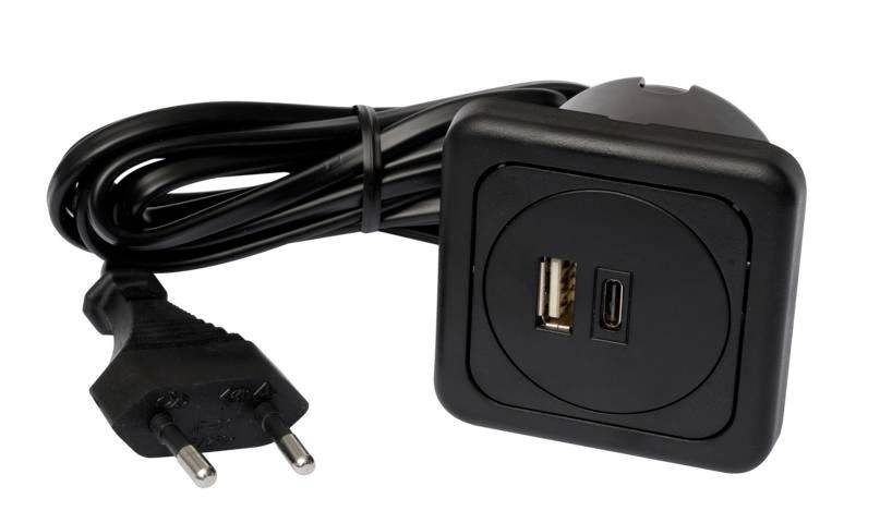 Čierna, štvorcová nabíjačka s USB a USB-C portom. Pripojený je k nej kábel s eurozástrčkou.
