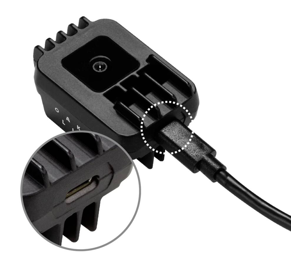 Čierna nabíjačka s zapojeným káblom. Zväčšený pohľad ukazuje konektor USB-C na boku zariadenia.