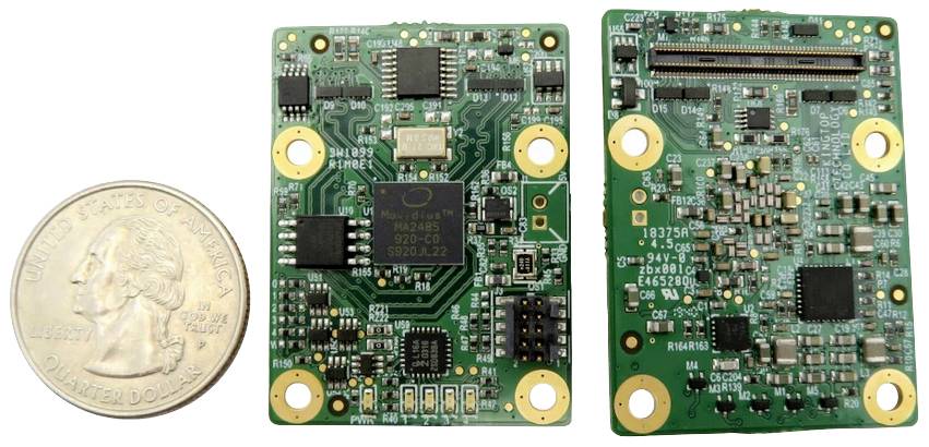 'Dve zelené elektronické dosky plošných spojov s rôznymi čipmi a obvodmi vedľa seba. Vľavo minca v hodnote 25 centov USA ako porovnanie veľkosti.'