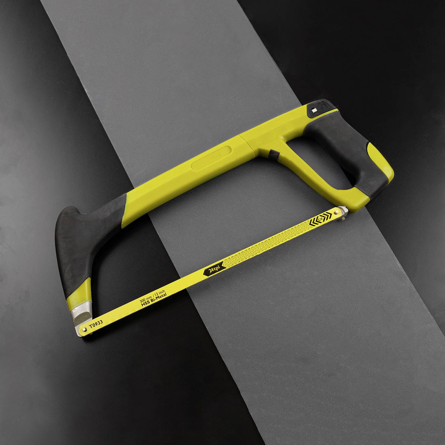 Žlto-čierna ručná píla leží na čiernom povrchu. Píla má ergonomickú rukoväť a kovový list.