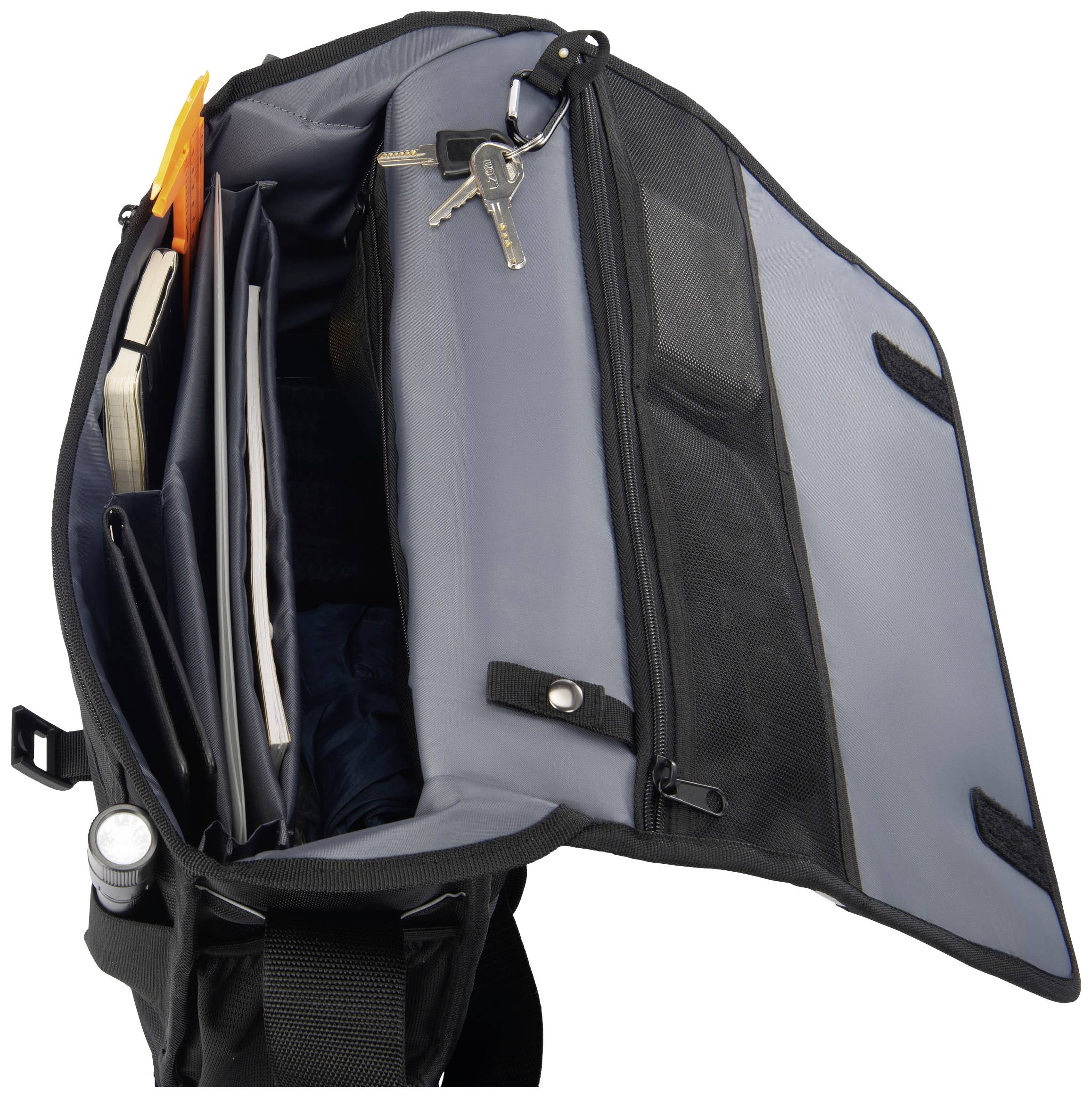 Otvorená čierna messenger taška s viacerými priehradkami, knihami a kľúčenkou zavesená na háčiku.