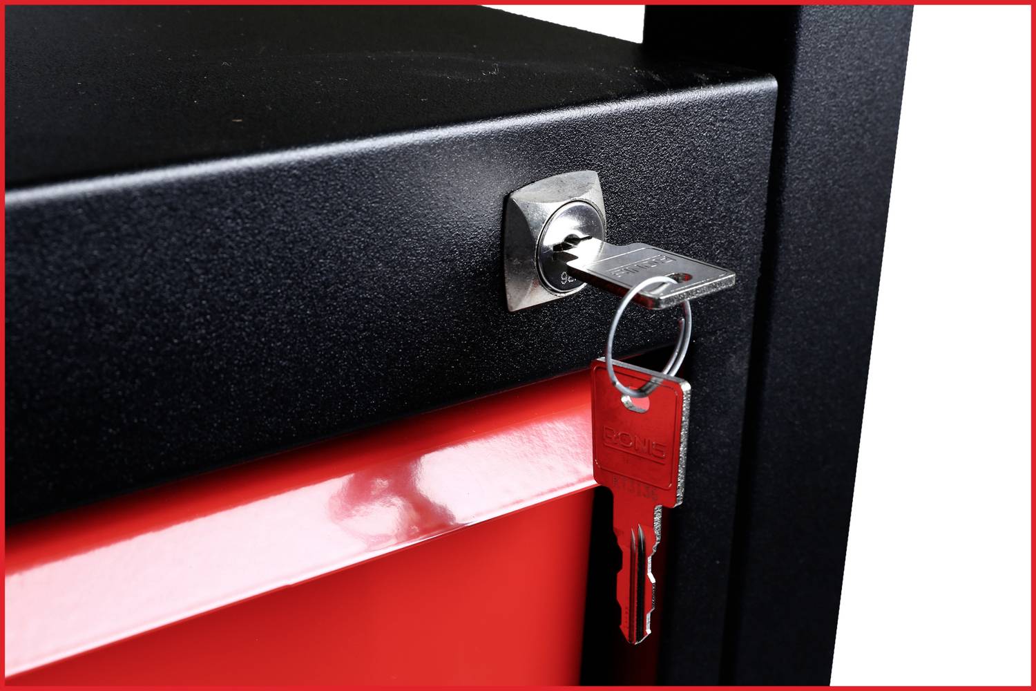 Čierny kus nábytku s strieborným kľúčom v zámke a červenou kľúčenkou visí na zväzku kľúčov.