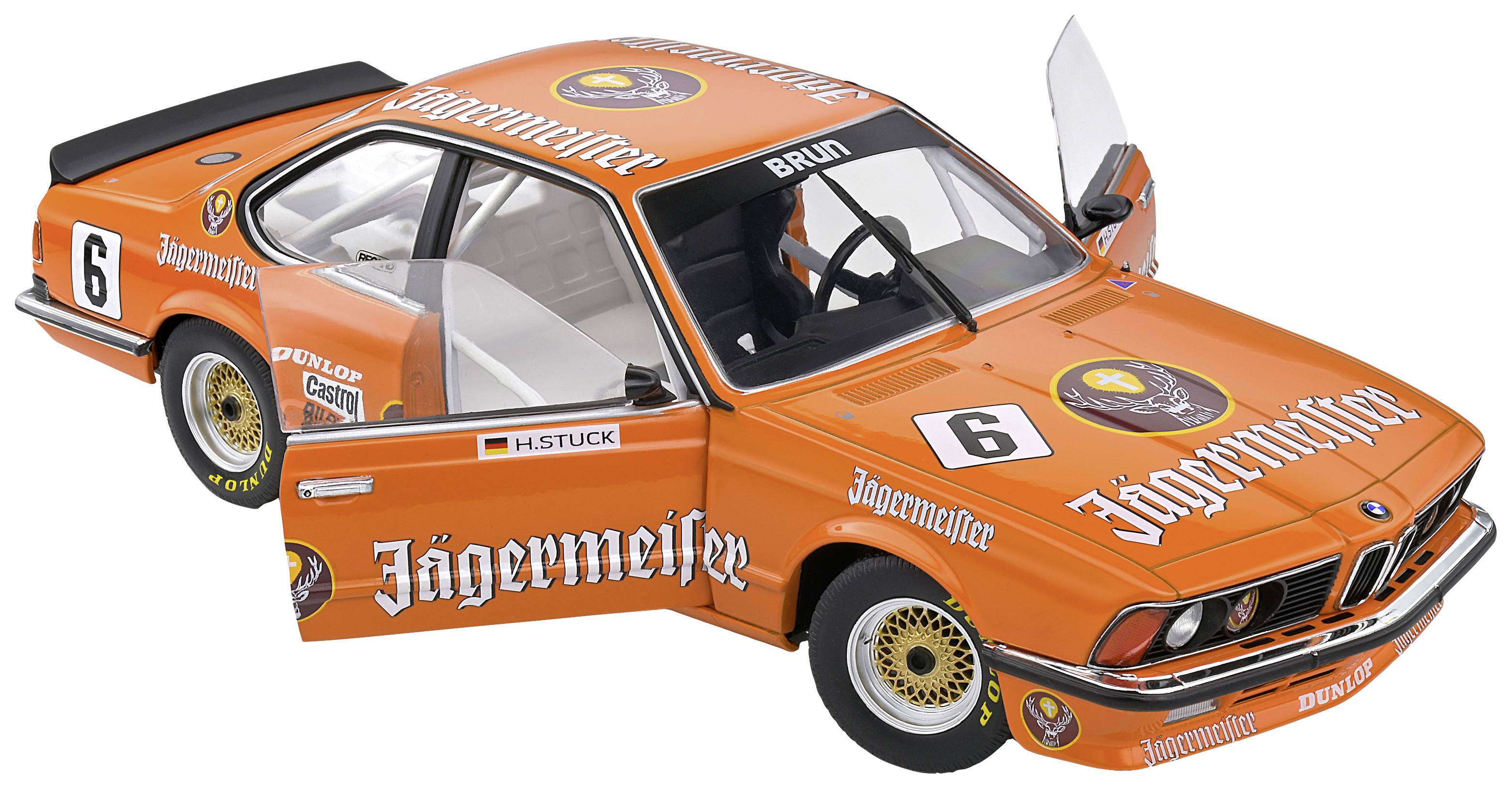 Model hračkárskeho pretekárskeho auta v oranžovej farbe s logom 'Jägermeister' a číslom 6. Dvere sú otvorené, auto stojí v pokoji.