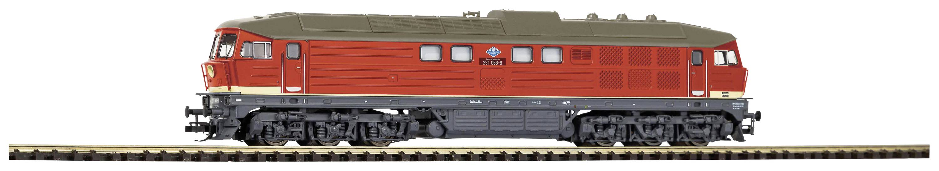 Červená modelová železničná lokomotíva stojí na koľajniciach. Má robustný dizajn s detailnými kolesami a výraznými vetracími mriežkami.