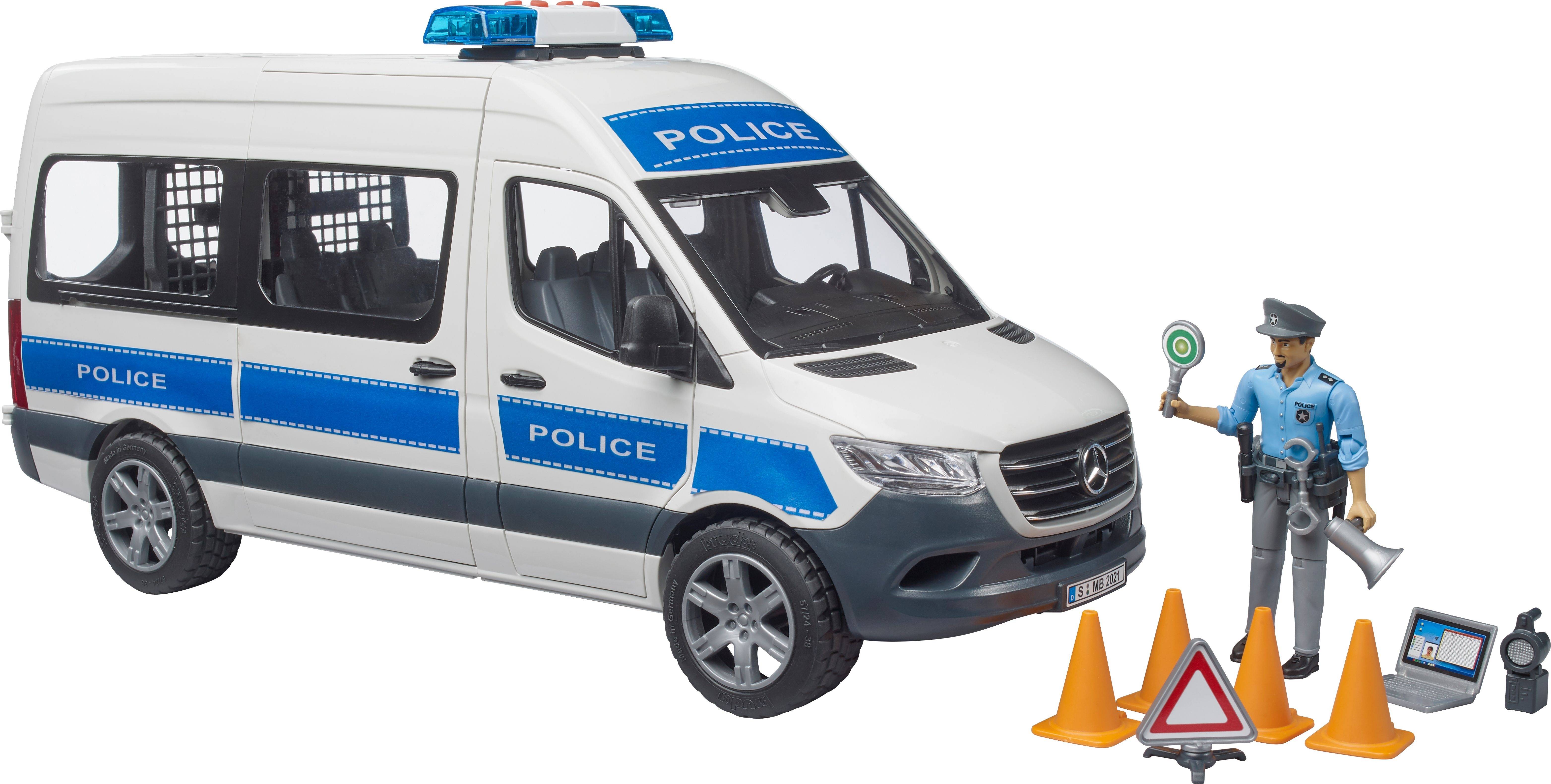 Biely policajný transportér s modrými pruhmi stojí vedľa policajnej figúry s dopravným kužeľom a stop-signálom.