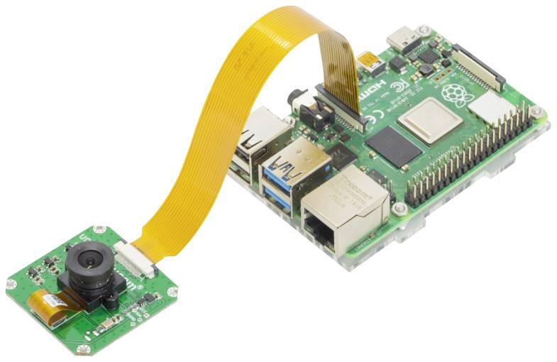 Zelená doska plošných spojov s pripojeným kamerovým modulom a oranžovou plochou páskovou káblovou prepojkou, vhodná pre DIY elektronické projekty.