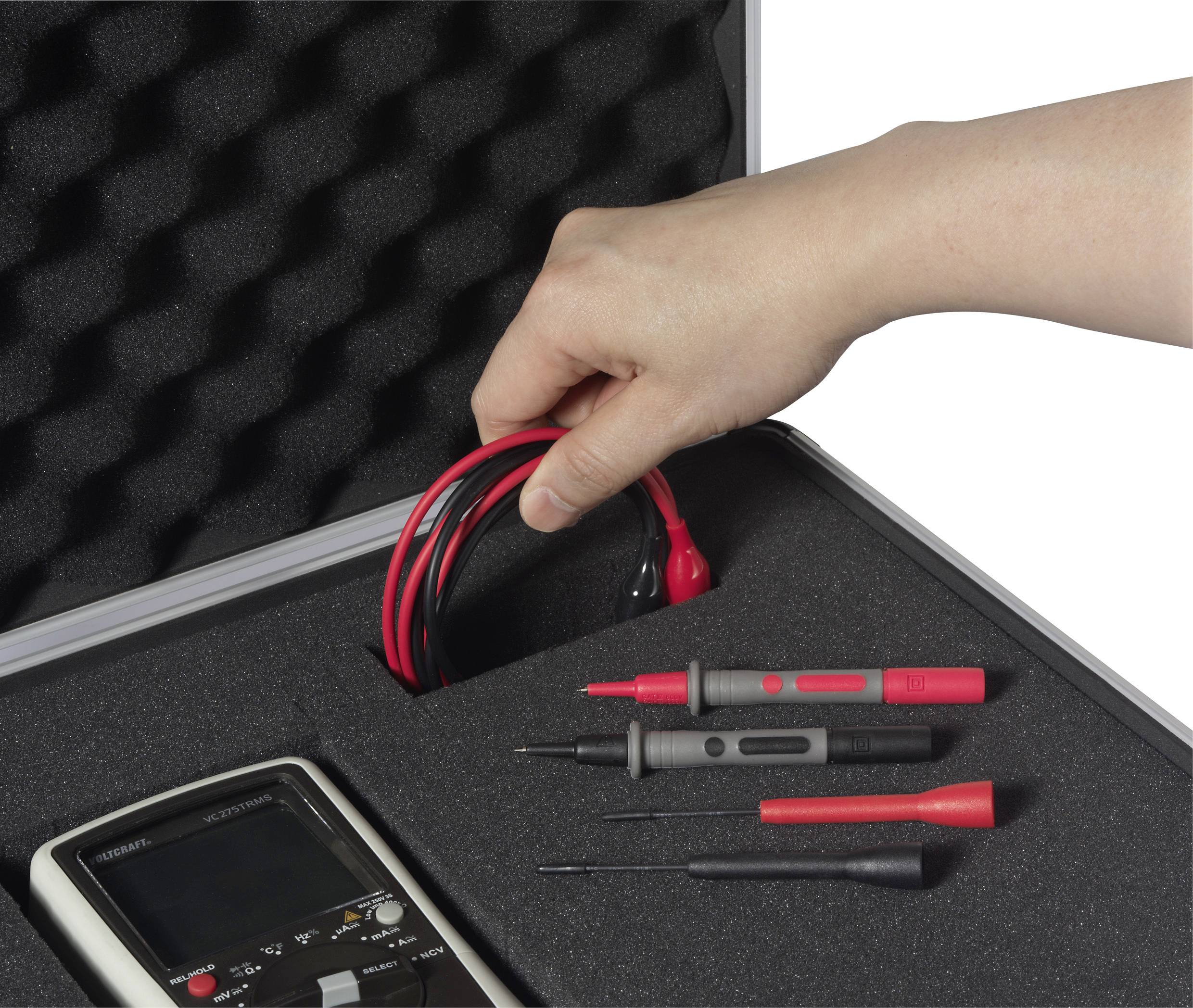 Ruka vyberá kábel z kufríka s penovou výplňou. Vedľa kábla ležia multimeter a meracie hroty.