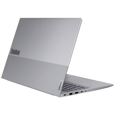 Strieborný notebook Lenovo, čiastočne otvorený, zobrazuje klávesnicu, niekoľko portov na boku a logo ThinkBook na veku.