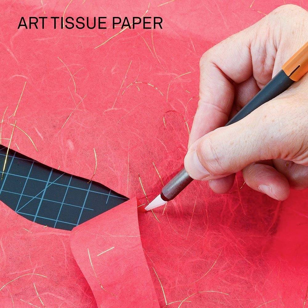 Ruka strieda cutter nožom červený papier, na ktorom je napísané 'ART TISSUE PAPER'.
