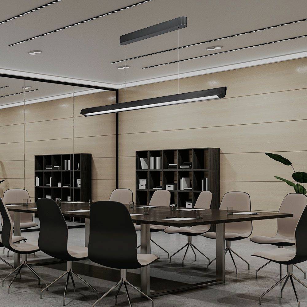 Moderná konferenčná miestnosť s veľkým stolom, ôsmimi stoličkami a policami plnými kníh a zakladačov. Jasné osvetlenie a rastliny dopĺňajú zariadenie.