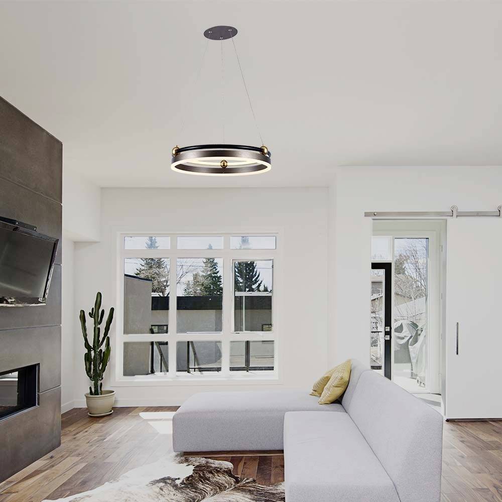 Moderná obývačka so sivou sedačkou, krbom, drevenou podlahou a veľkým oknom. Od stropu visí okrúhly luster.