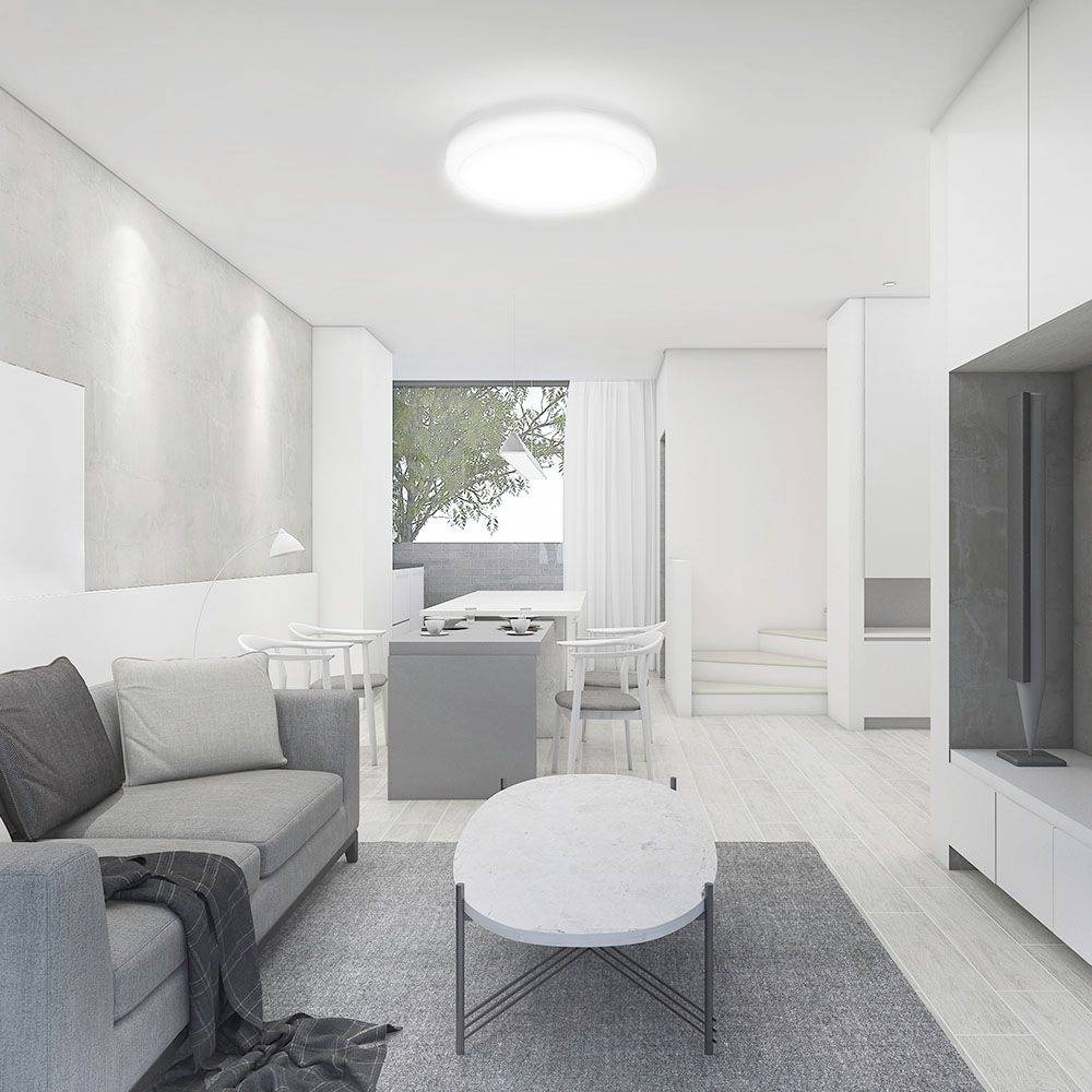 Moderná obývačka v neutrálnych tónoch so sivou sedačkou, oválnym konferenčným stolíkom a výhľadom na jedálenský priestor a okno so stromom vonku.