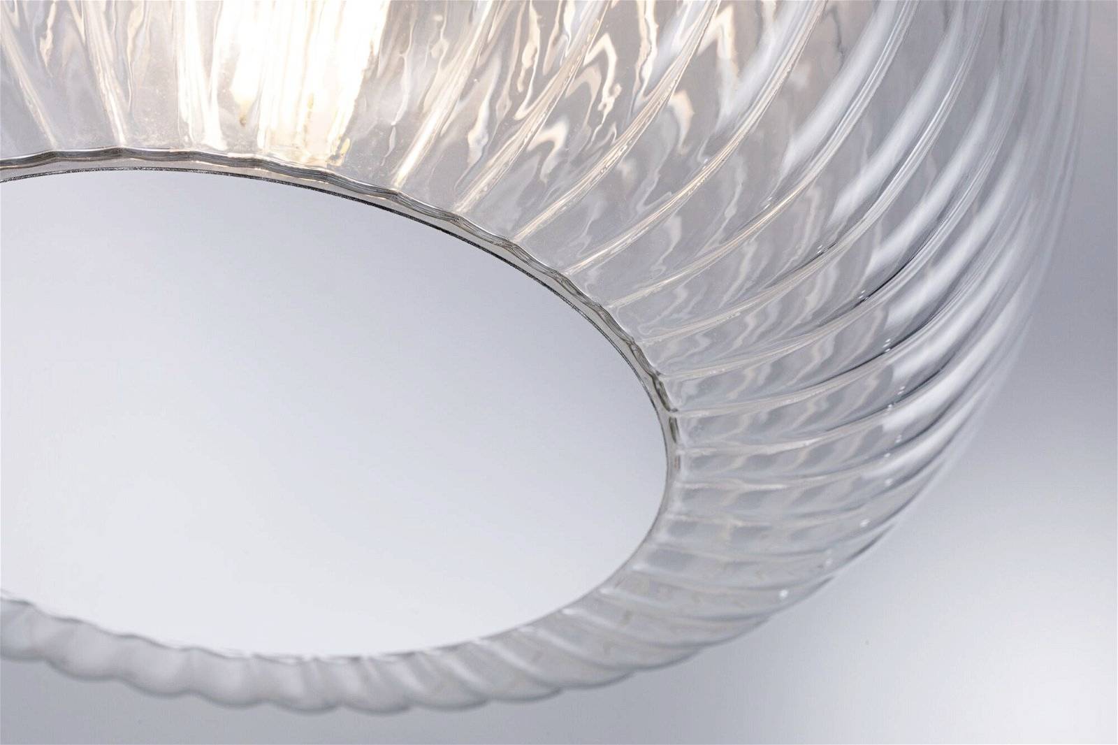 Priehľadná, štruktúrovaná sklenená lampa visia zo stropu a vyžaruje mäkké, difúzne svetlo.