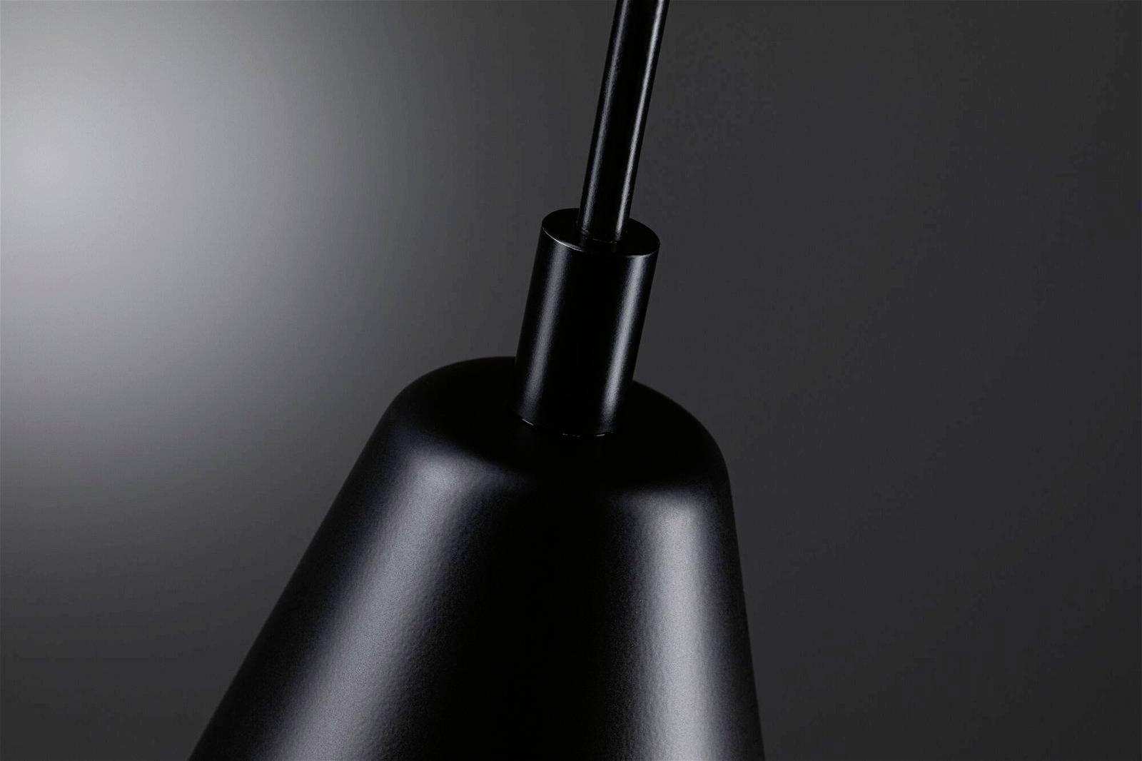 Čierna lampa pred tmavosivým pozadím, viditeľná horná časť a kábel. Elegantný, minimalistický dizajn.