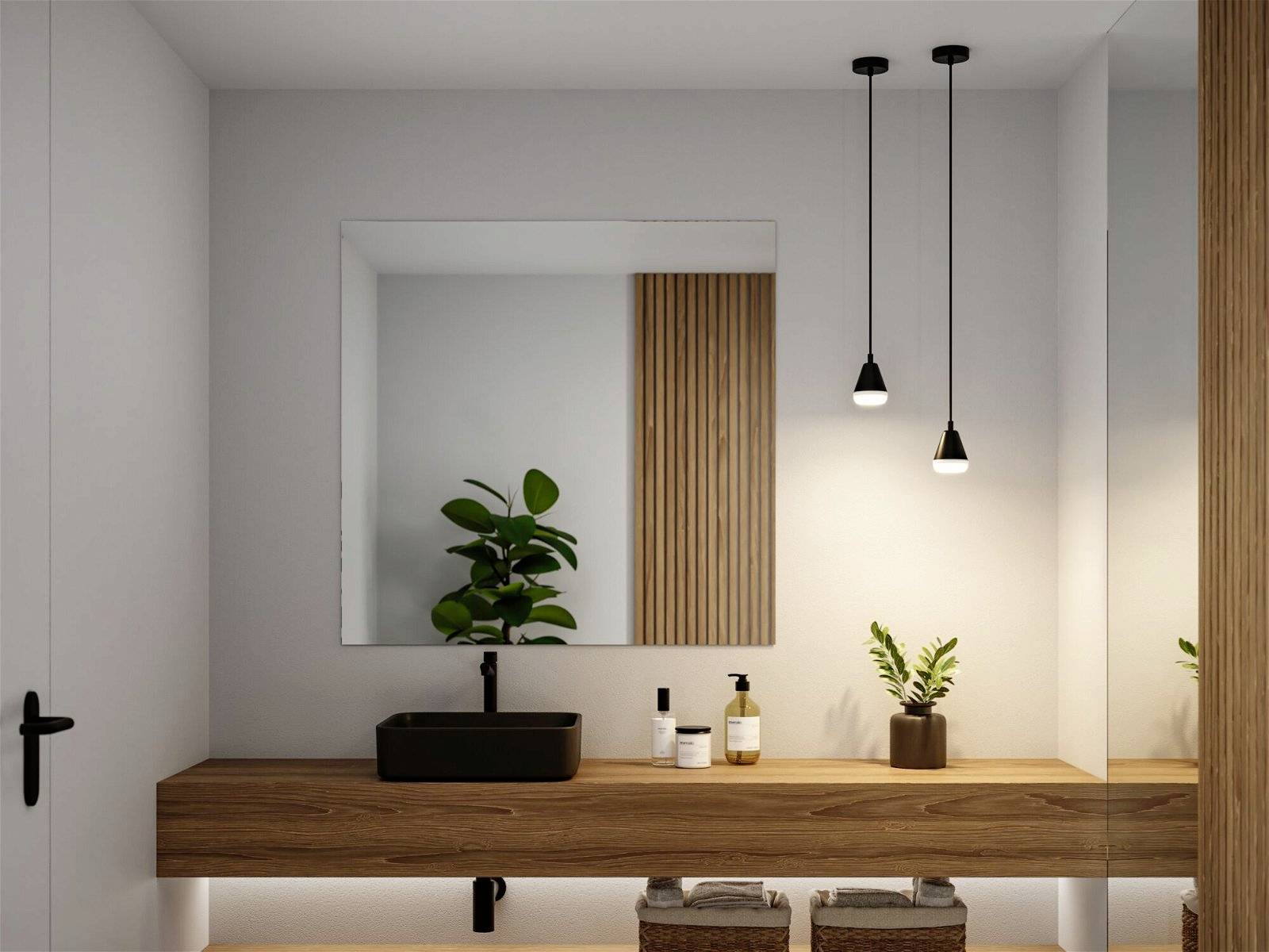 Moderná kúpeľňa s dreveným umývadlovým stolíkom, čiernym umývadlom a veľkým zrkadlom. Závesné lampy a rastliny ako dekorácia.